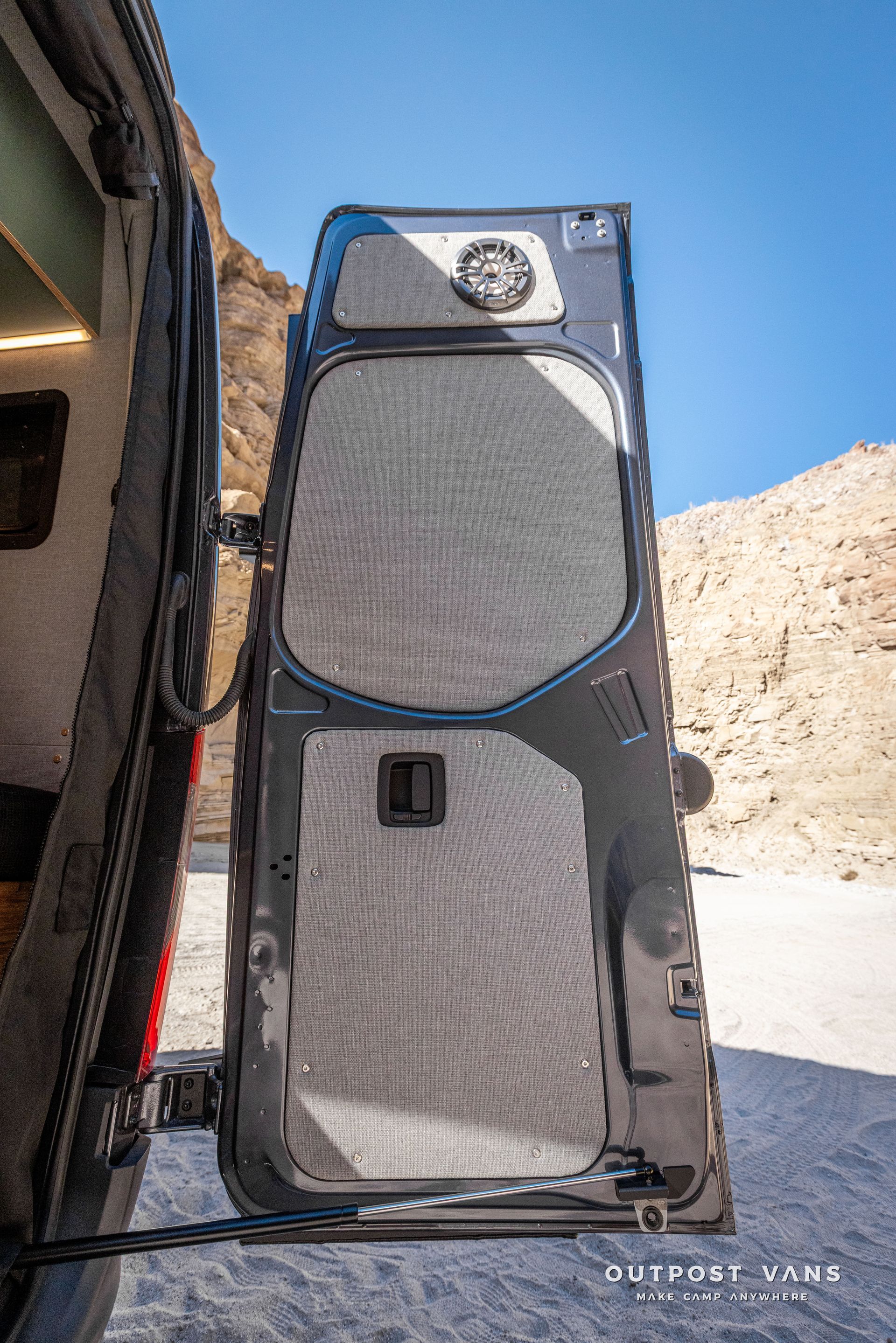 A van with the door open is parked in the desert.