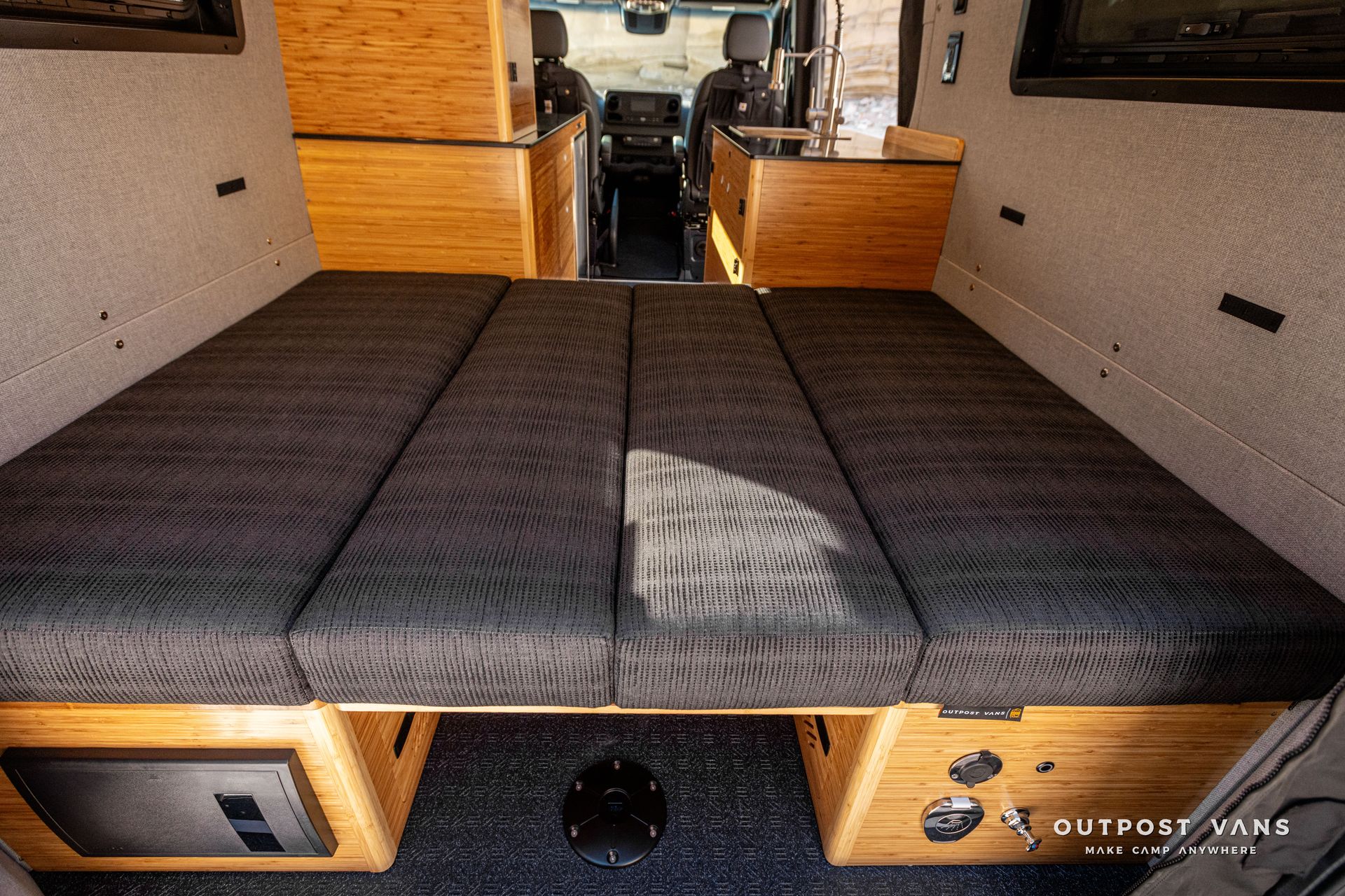 The back of a van with its doors open and a dinette converted bed in the back.