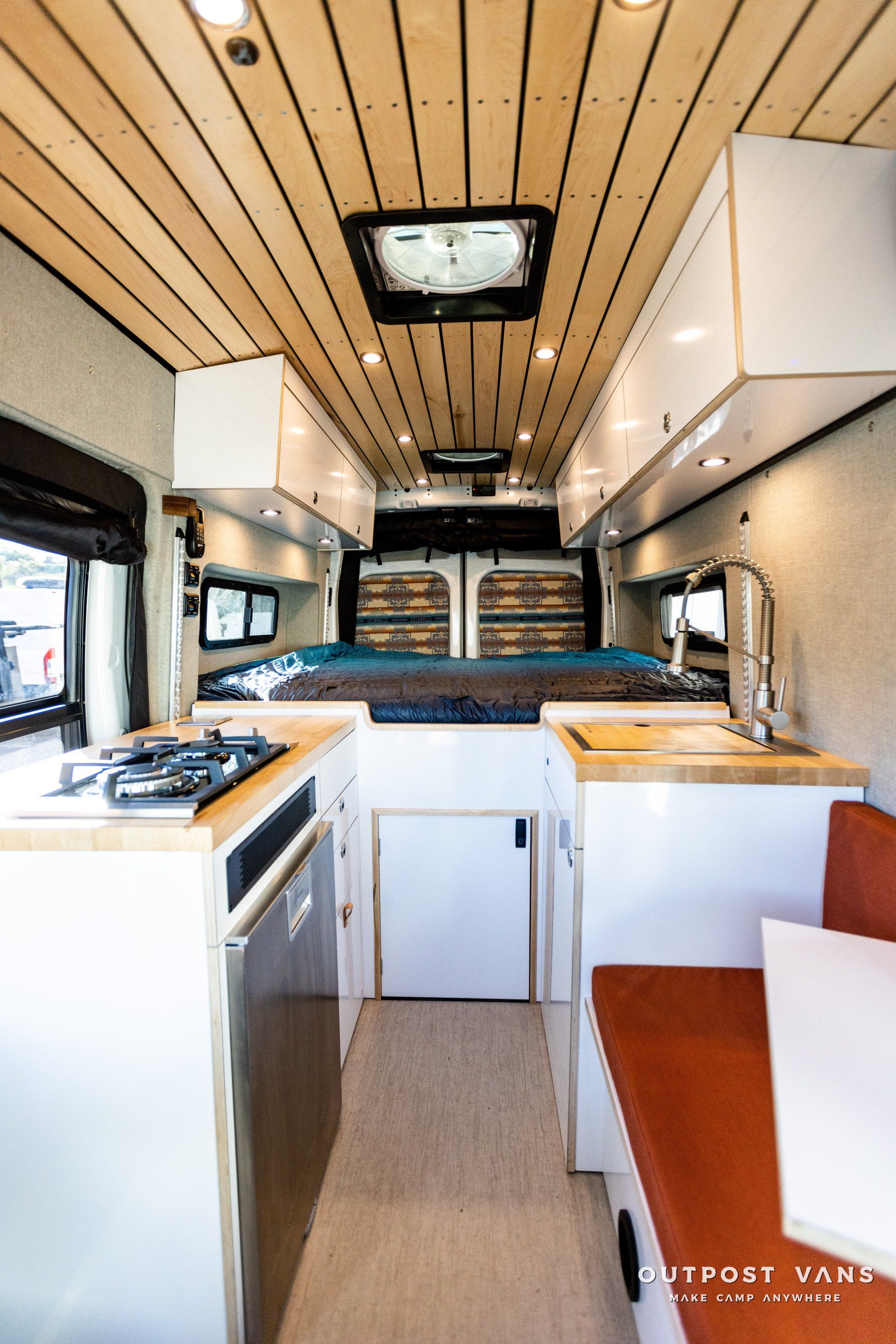 the inside of a camper van with a kitchen and a bed .