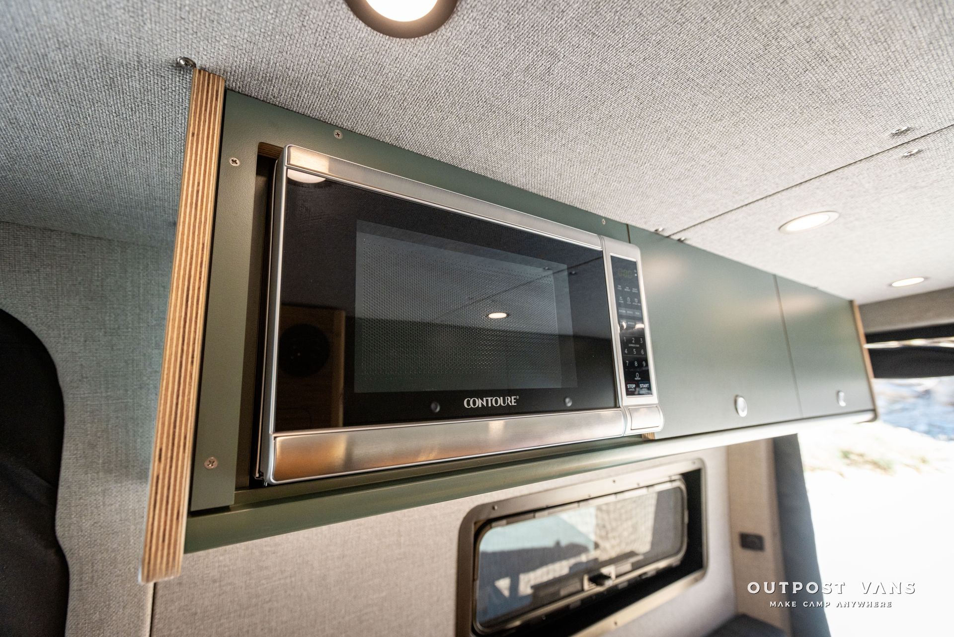 A microwave oven is built into the ceiling of a van.