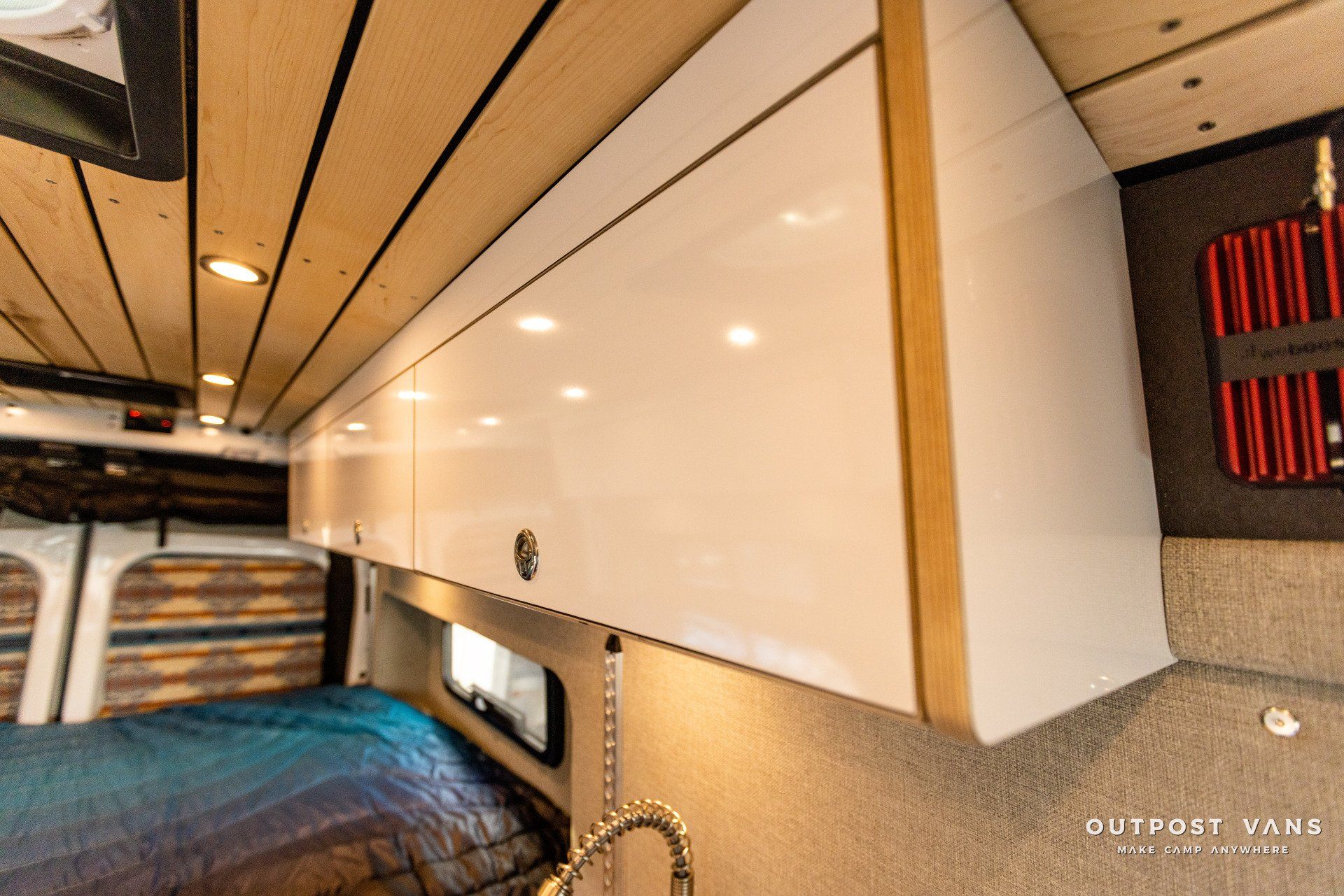 a camper van with white cabinets and a bed