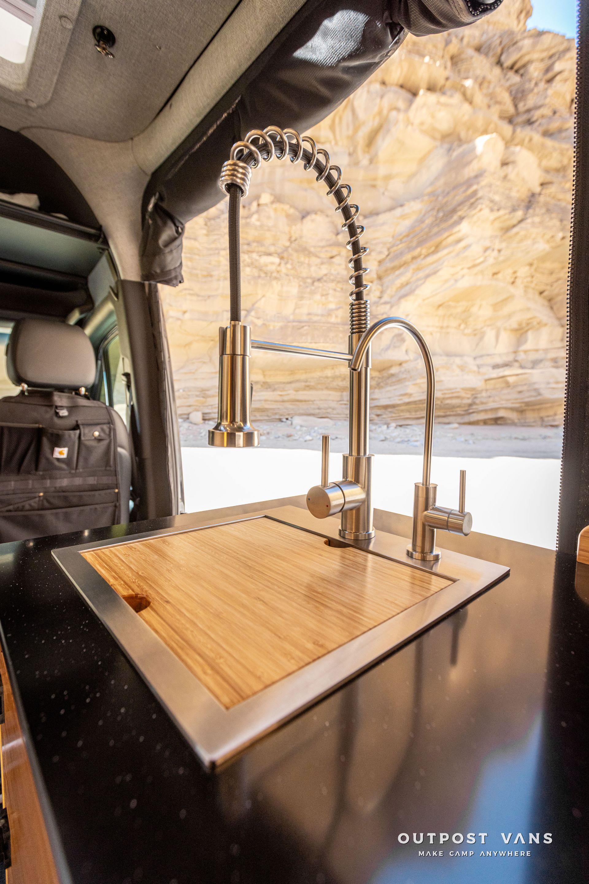 A kitchen sink with a wooden counter top and a faucet in a van.