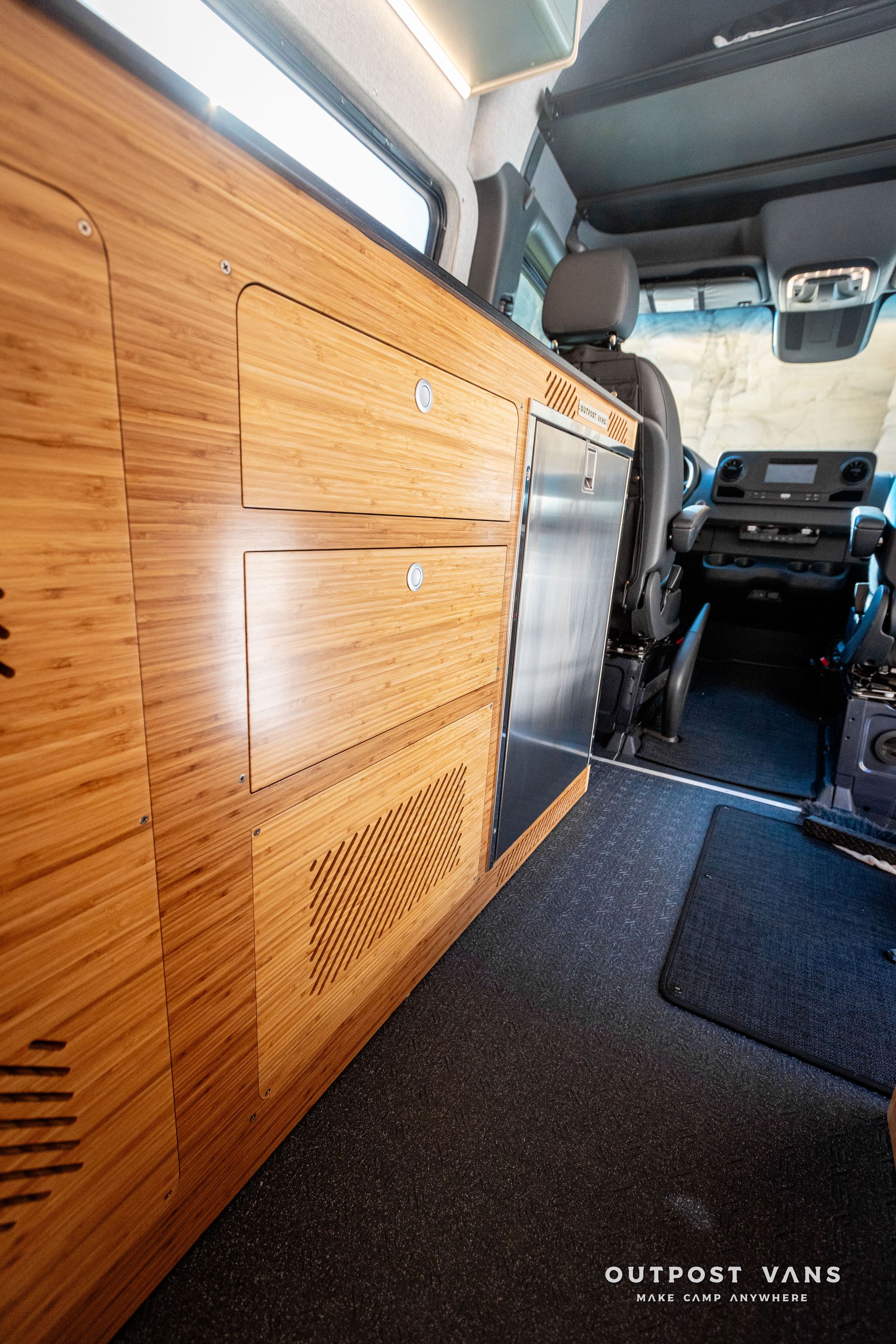 The inside of a van with wooden cabinets and drawers.