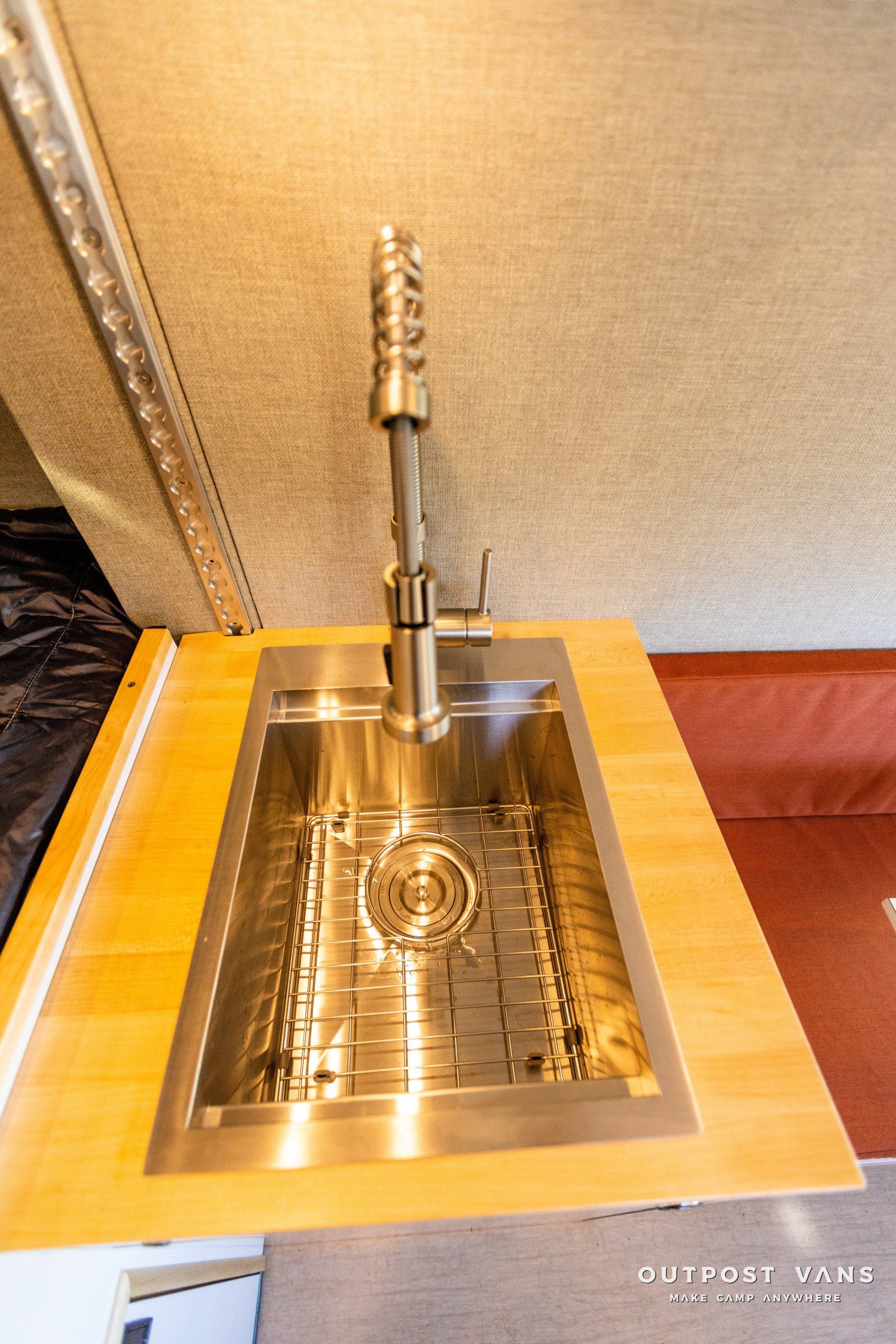 a stainless steel sink is sitting on top of a wooden counter .