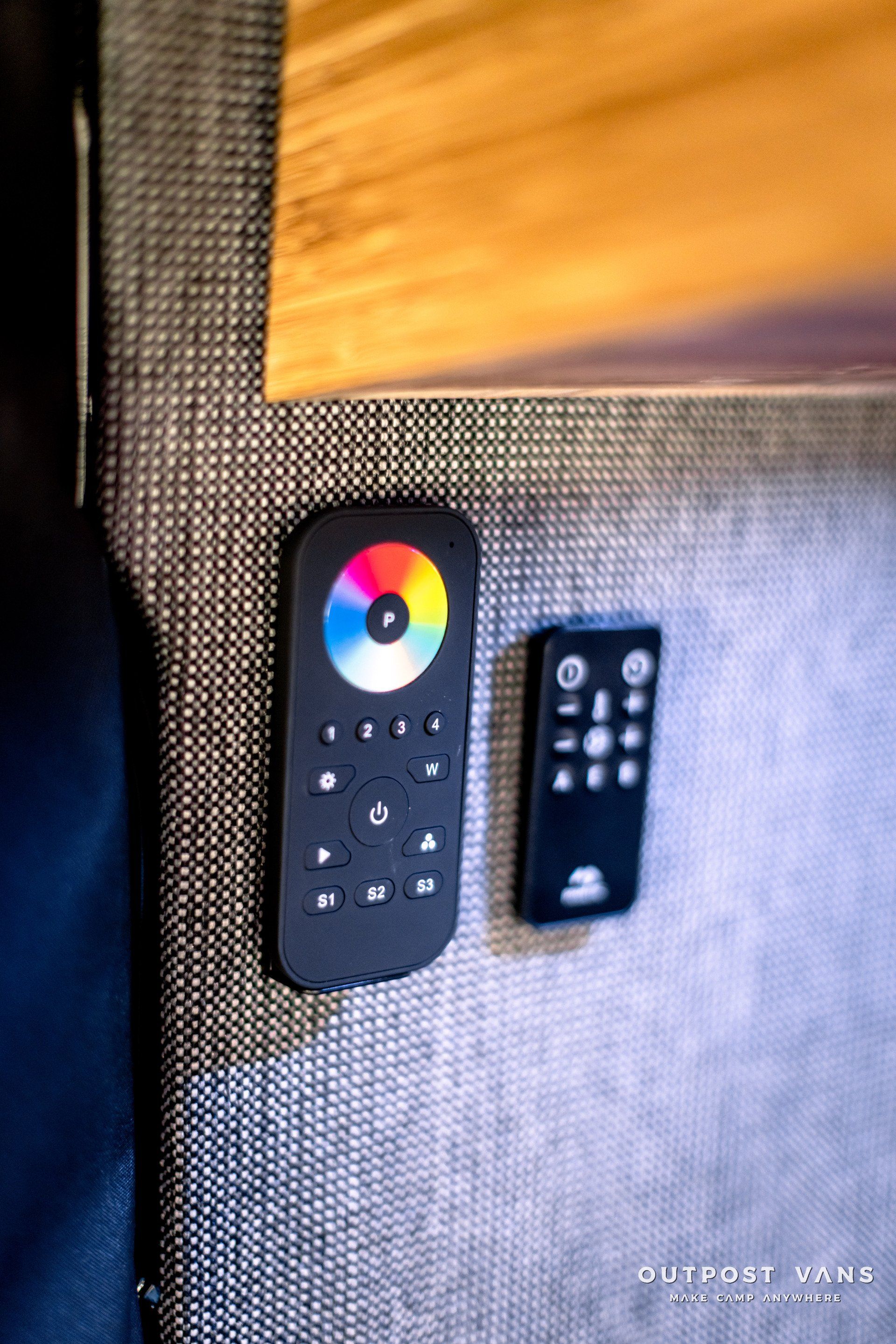 A remote control is sitting on a wall next to another remote control.