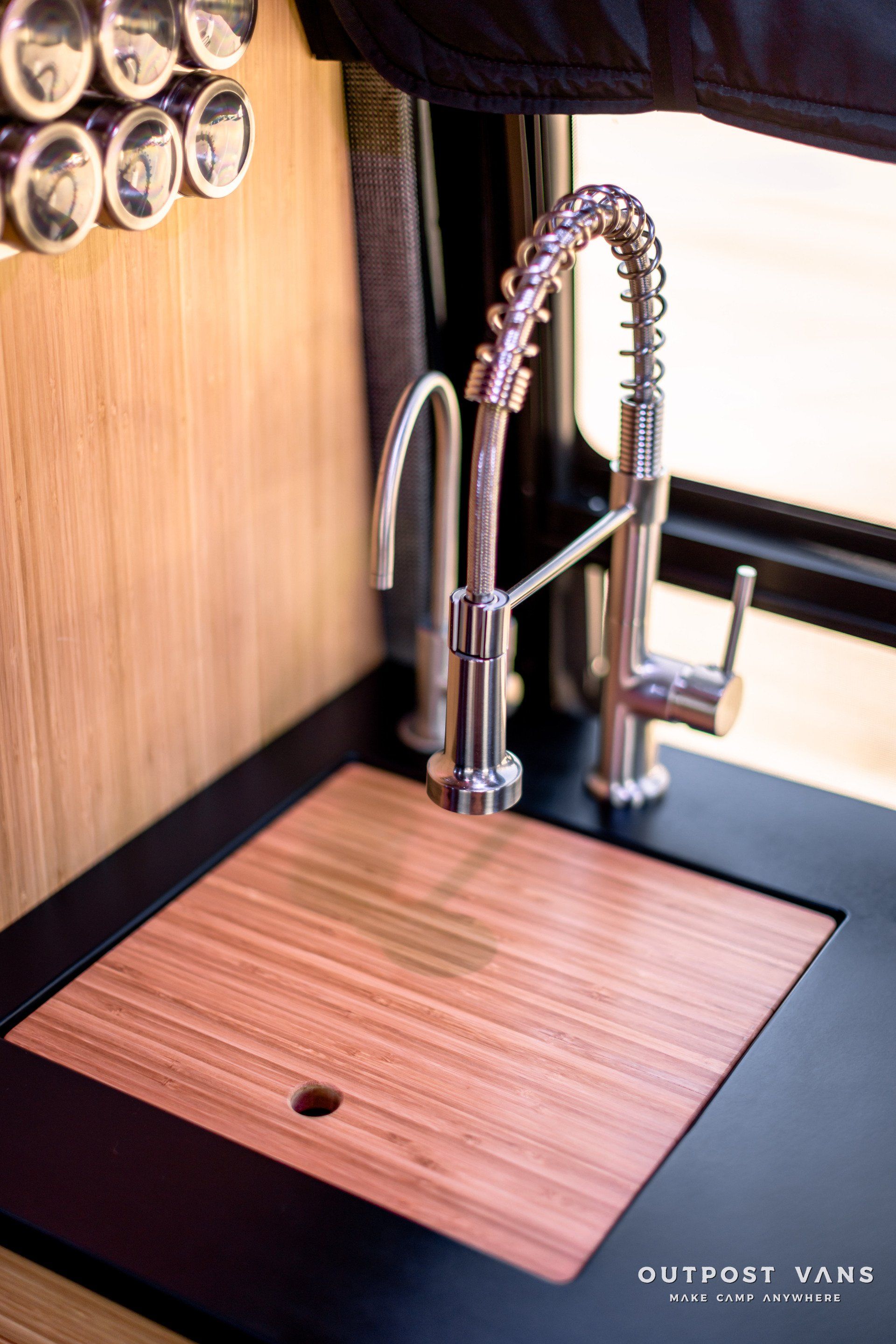 A kitchen sink with a wooden cutting board and a faucet.