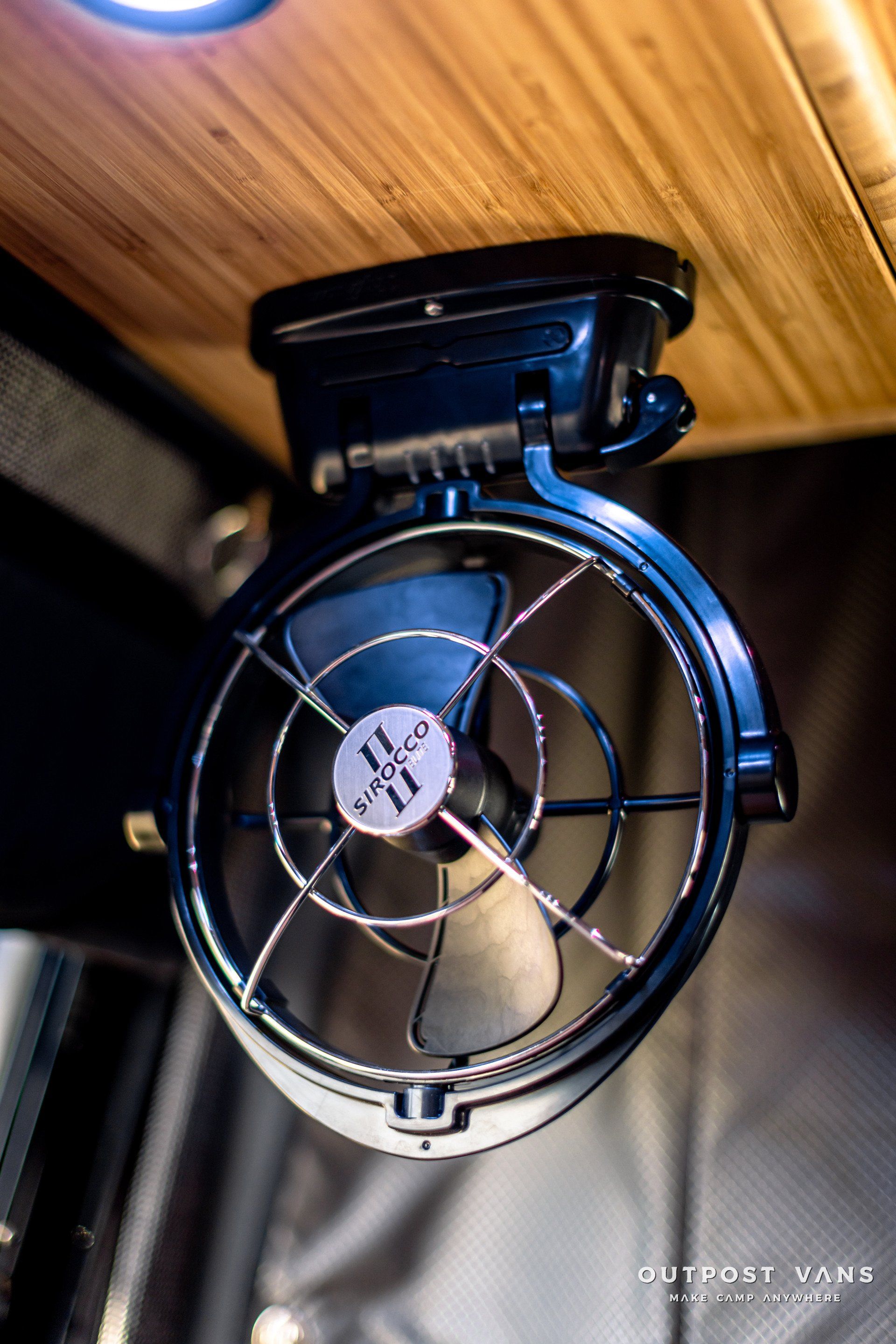 A small fan is hanging from the ceiling of a car.