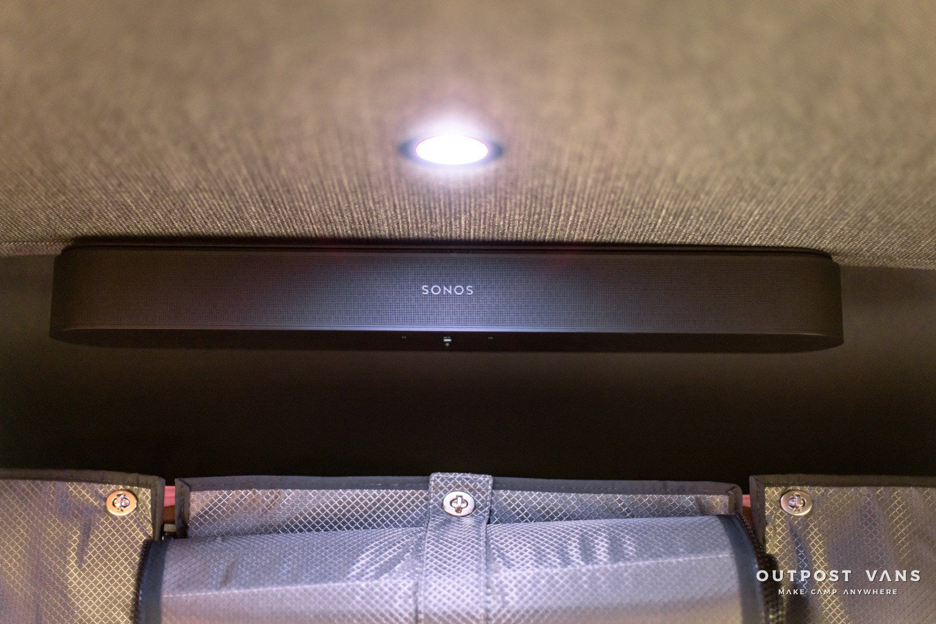 A speaker is mounted to the ceiling of a van