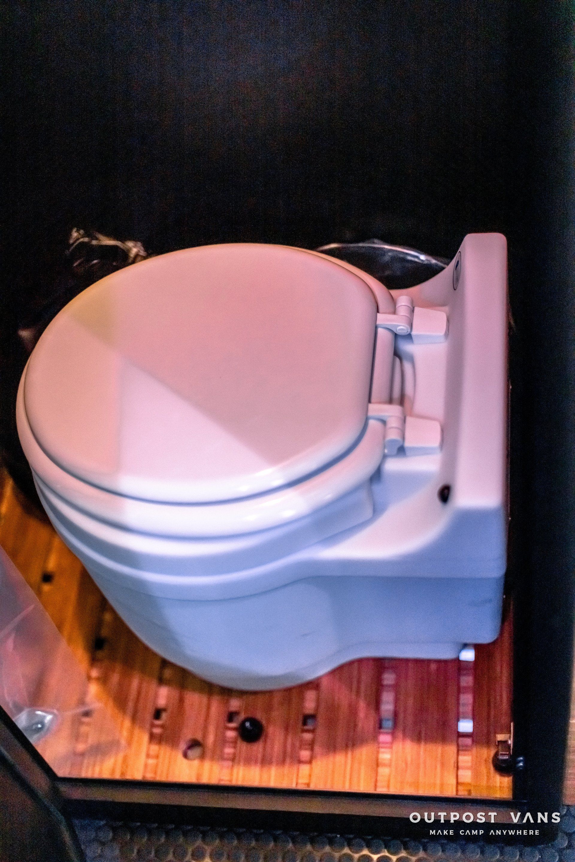 A white toilet is sitting on a wooden floor