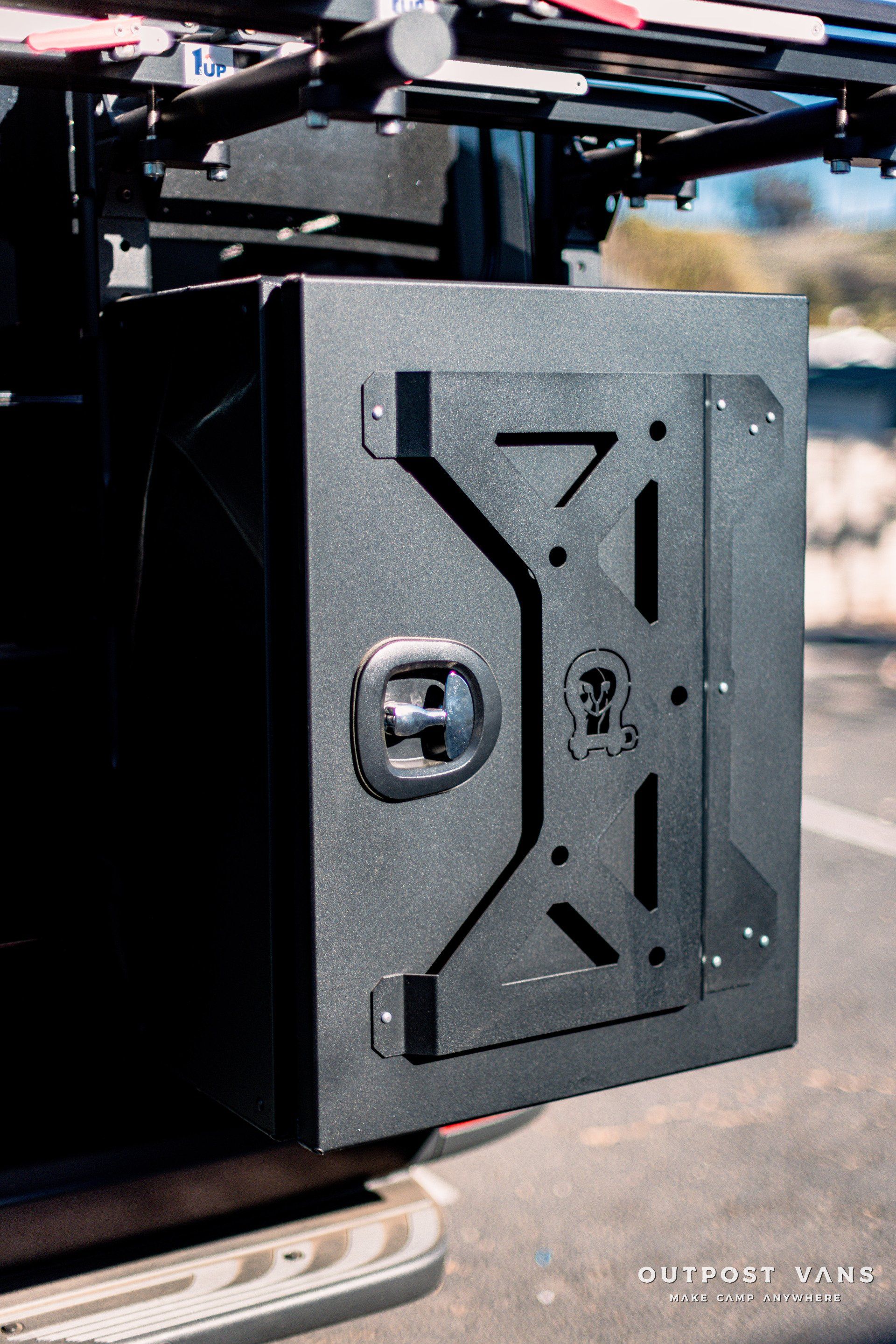 A black metal box is sitting on the back of a truck.