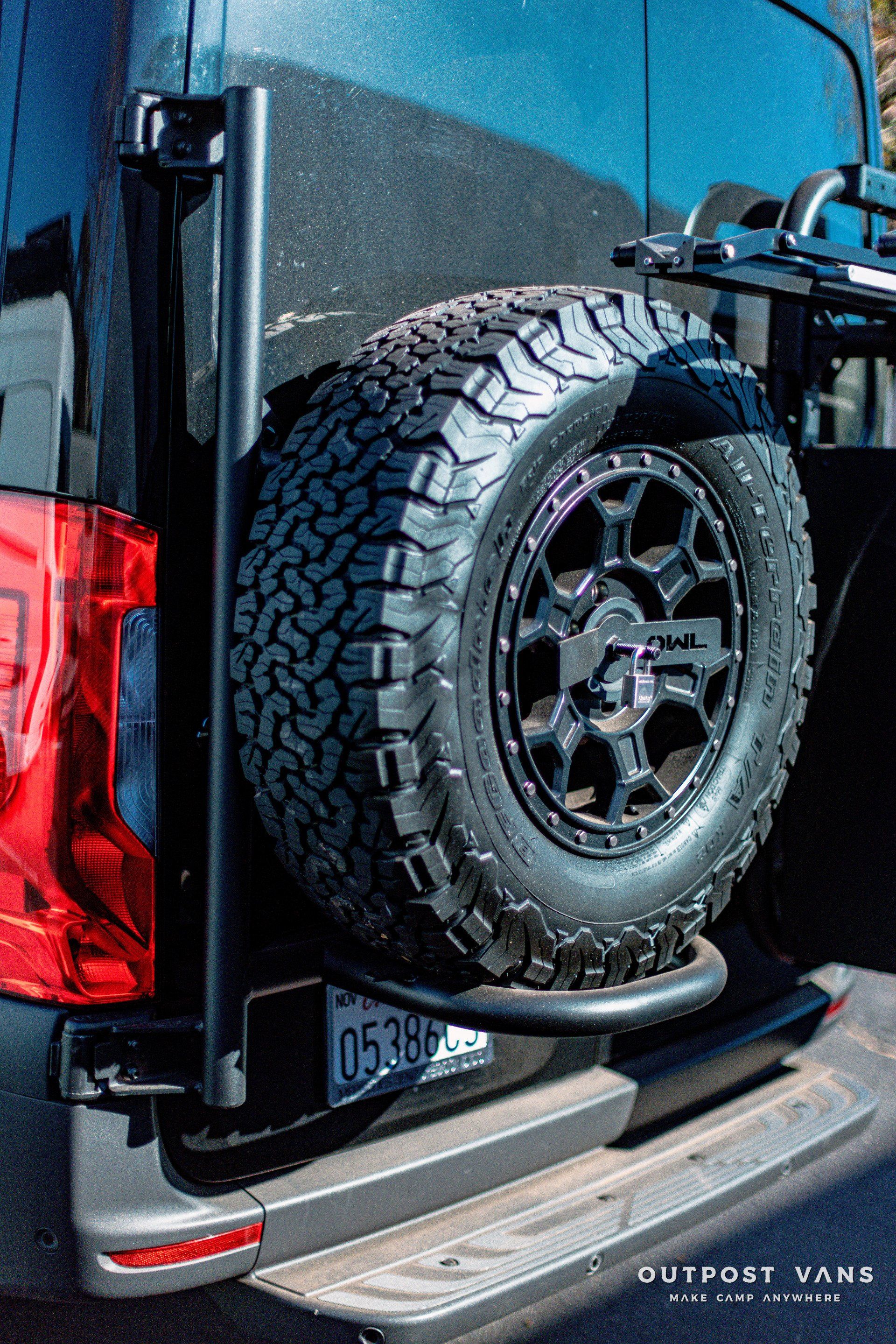 A black van with a spare tire attached to the back of it.