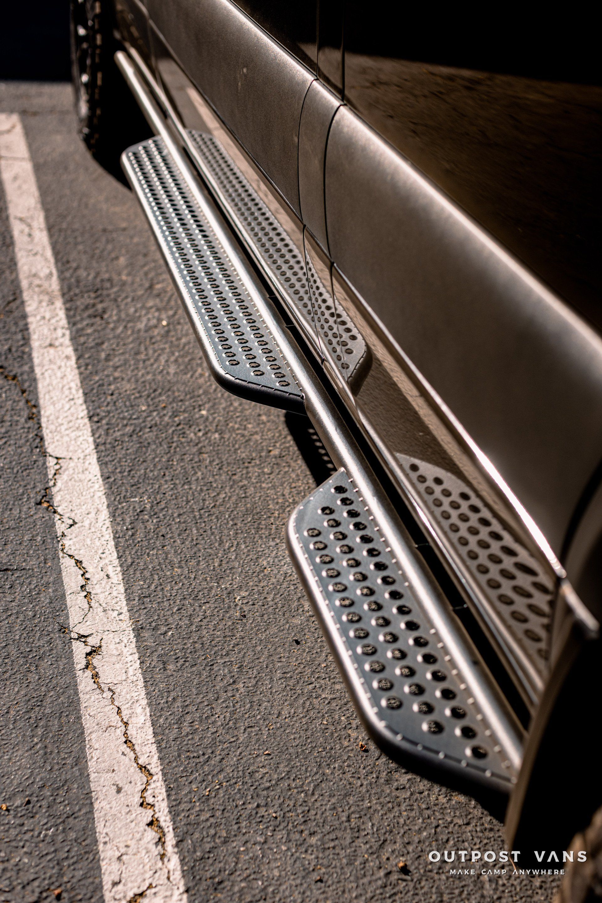 A car with side steps is parked in a parking lot