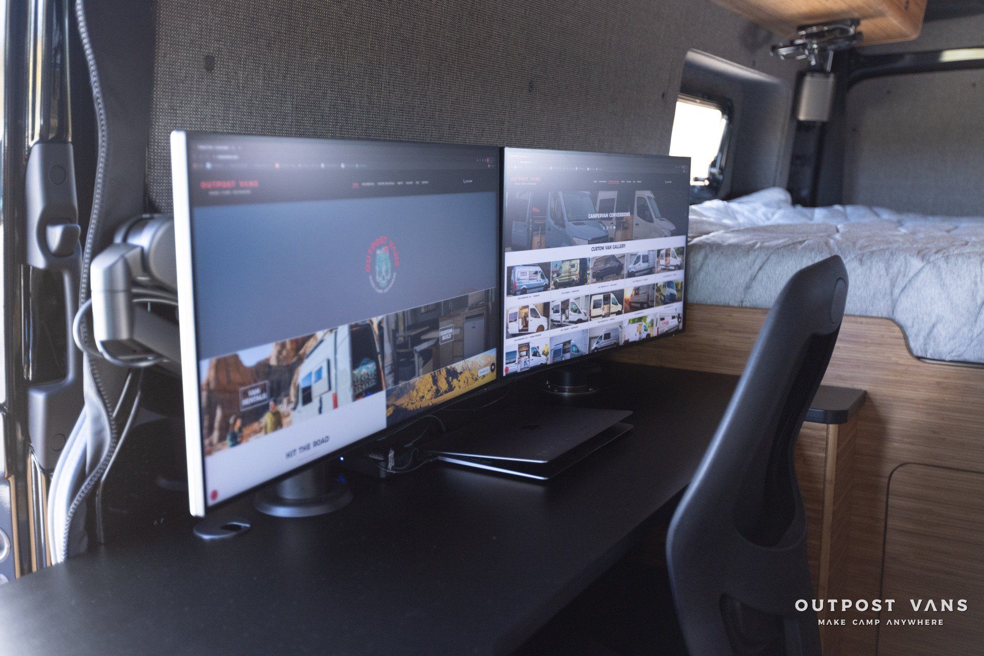 Two computer monitors are sitting on a desk in a van.