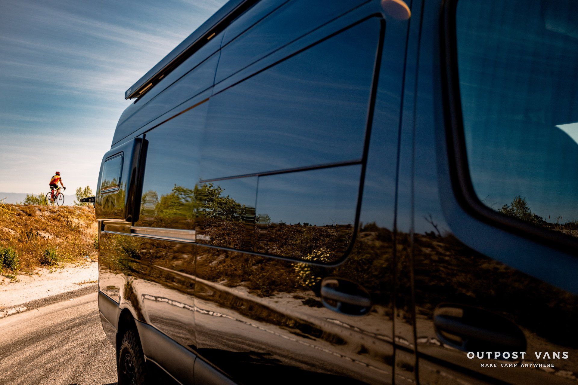 A black van is parked on the side of a road.