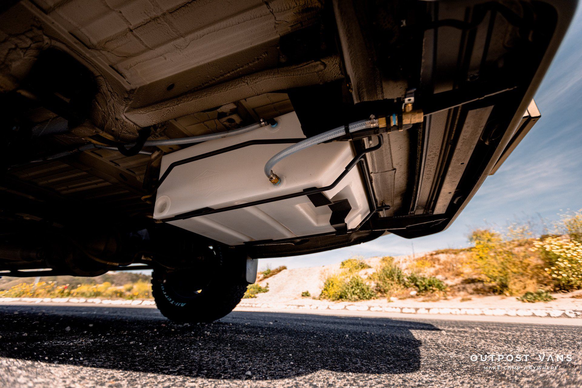 A large tank is attached to the underside of a car.