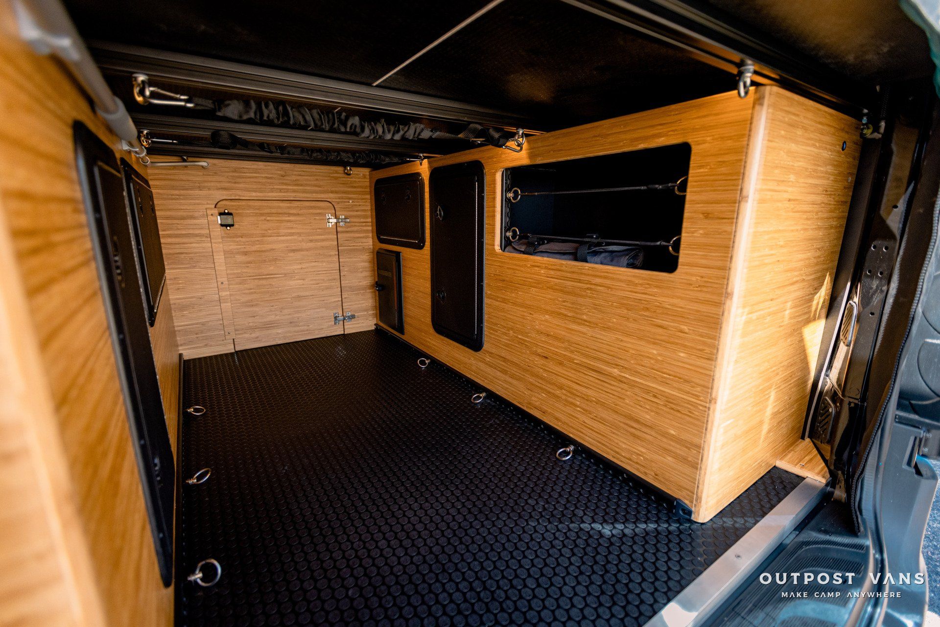 The inside of a trailer with a wooden wall and a black floor.