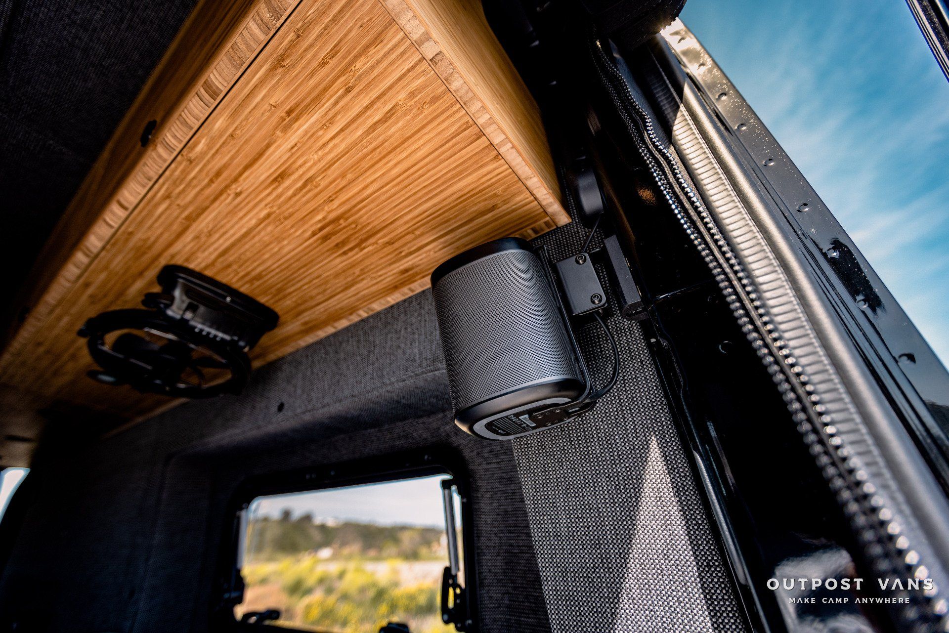 A van with a wooden shelf and speakers on the ceiling.