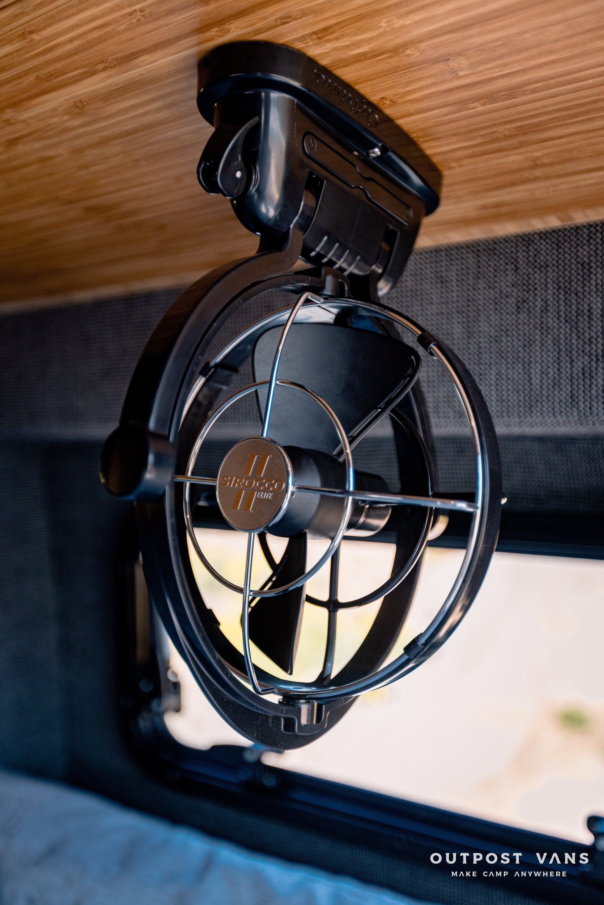 A small fan is hanging from the ceiling of a van.