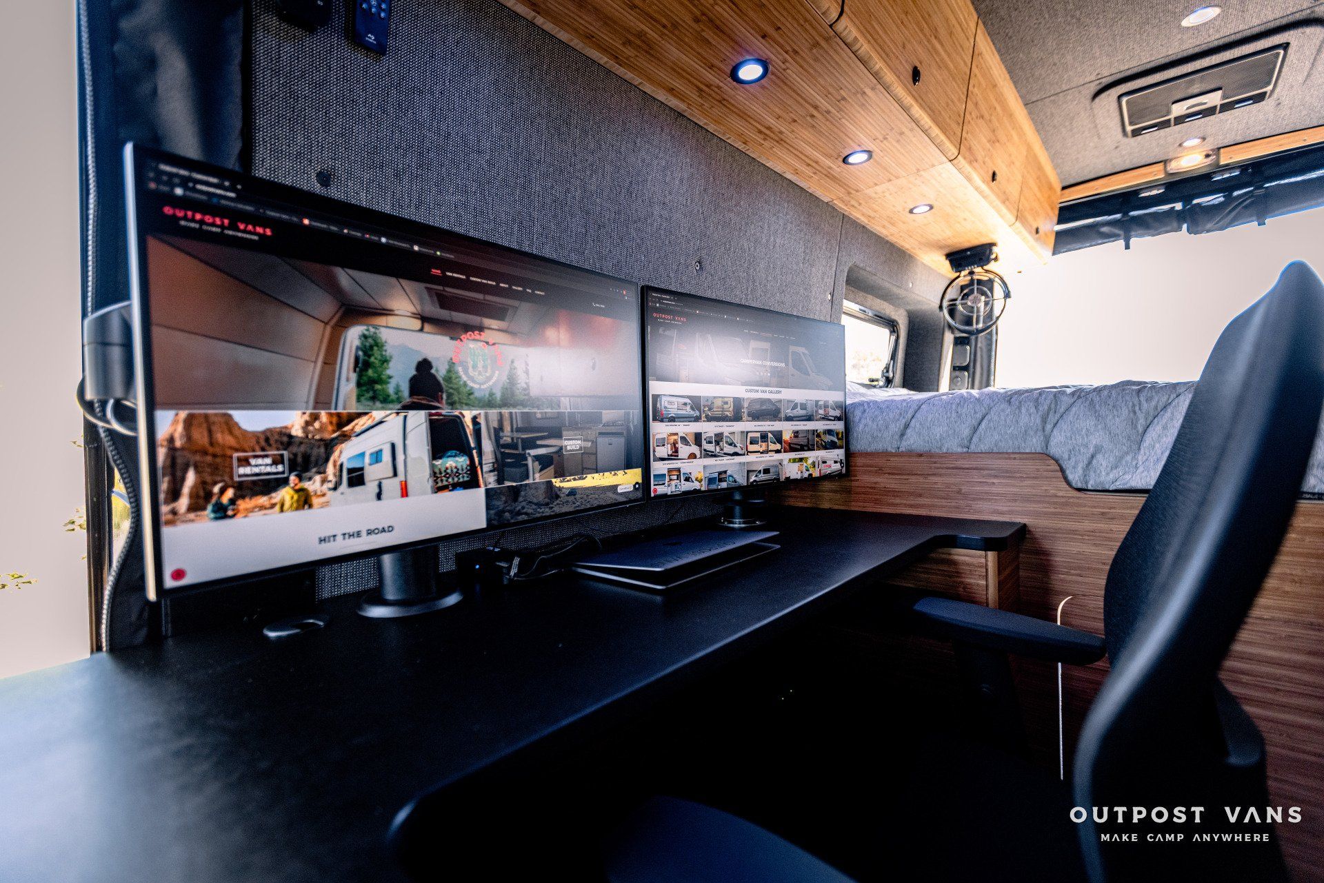 A computer desk with two monitors and a chair in a van.