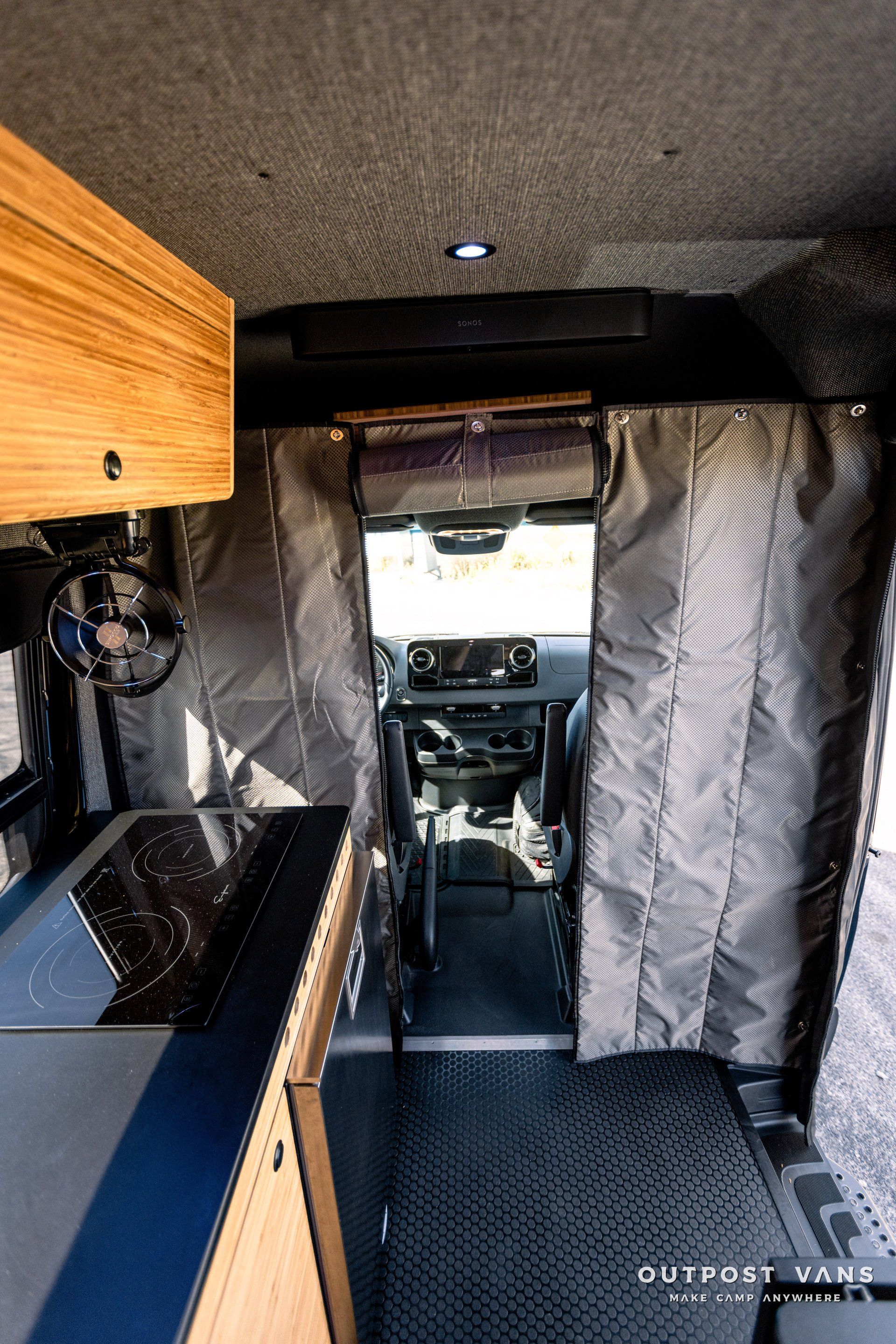The inside of a camper van with a kitchen and curtains.