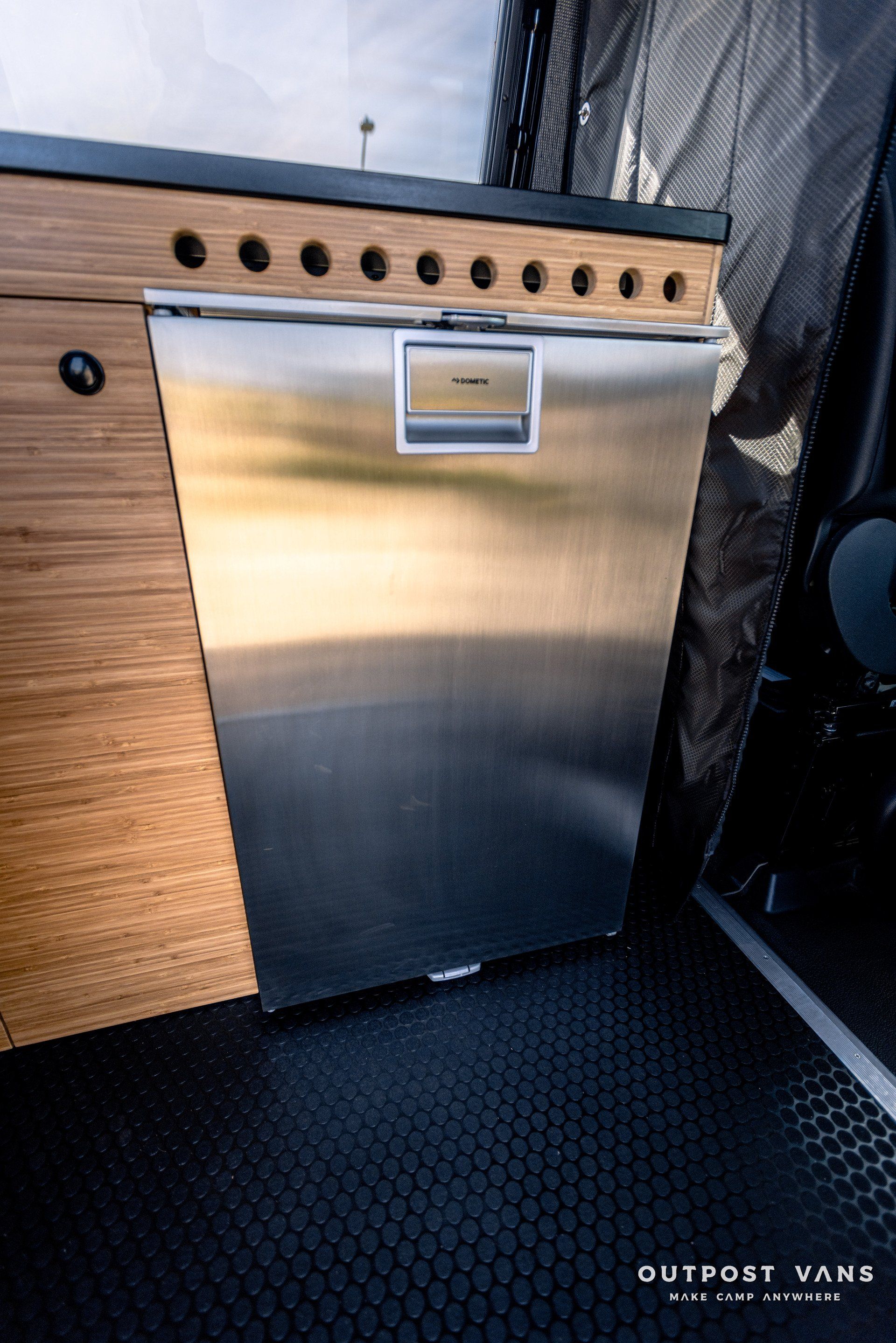 A stainless steel dishwasher is in a kitchen in a van.