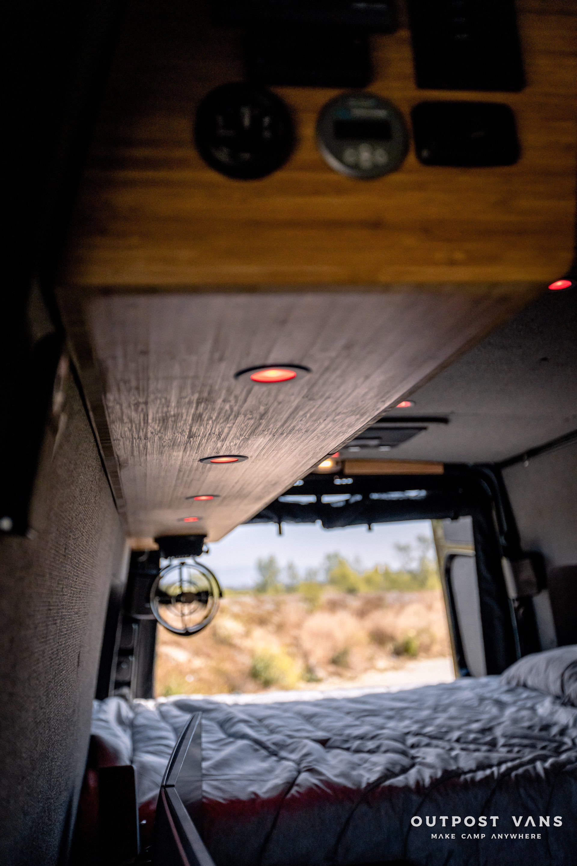 The inside of a van with a bed and a wooden ceiling.
