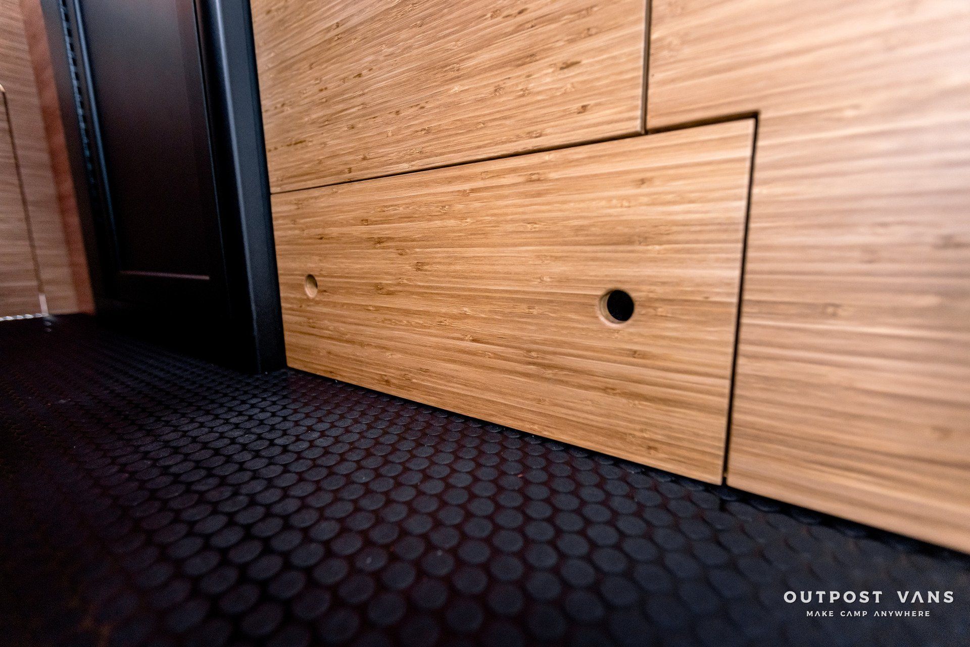 A wooden wall with a black tile floor and a door.
