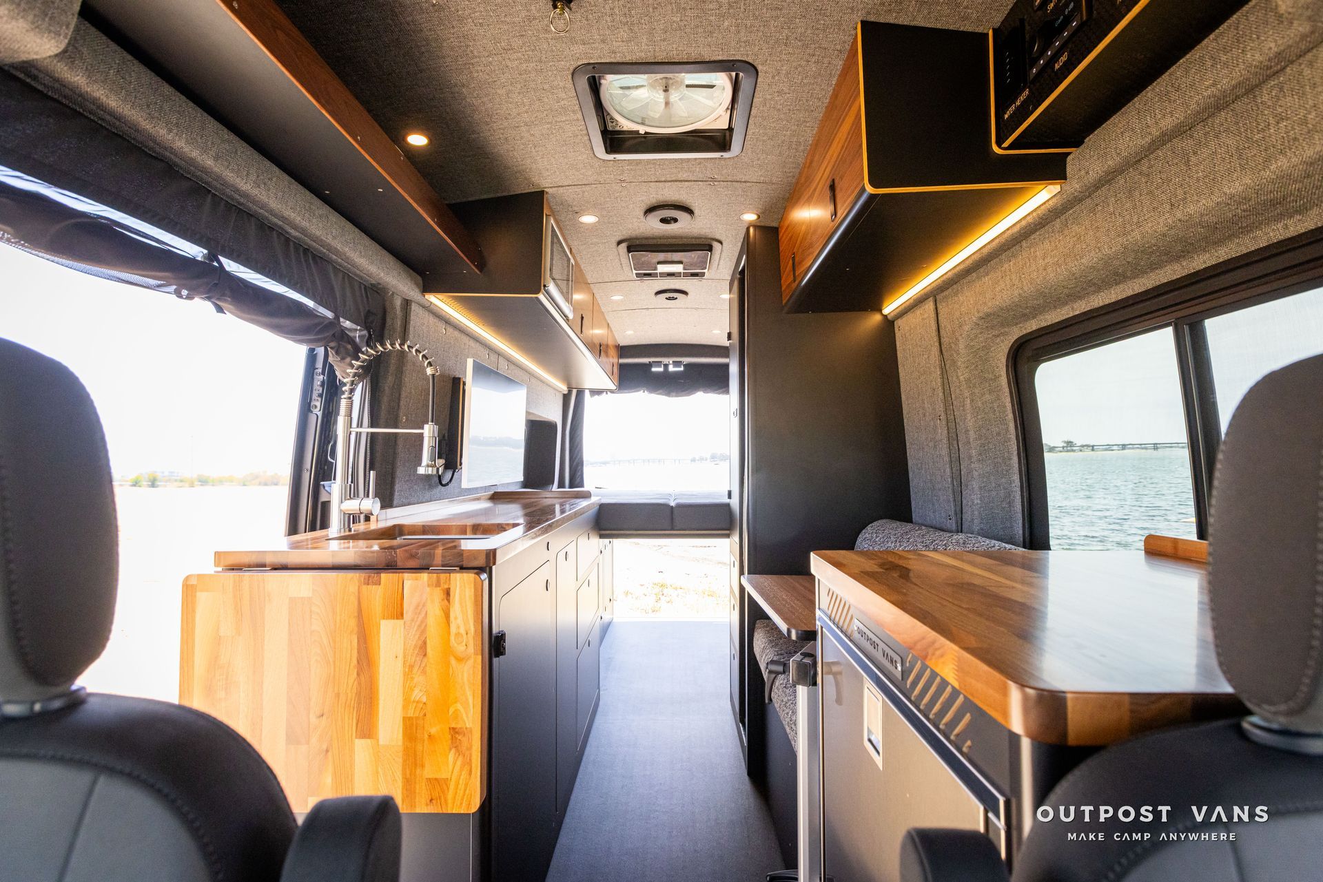 Outpost Vans custom built camper van Ford Transit 148 AWD. The inside of a camper van with wooden counter tops and cabinets.