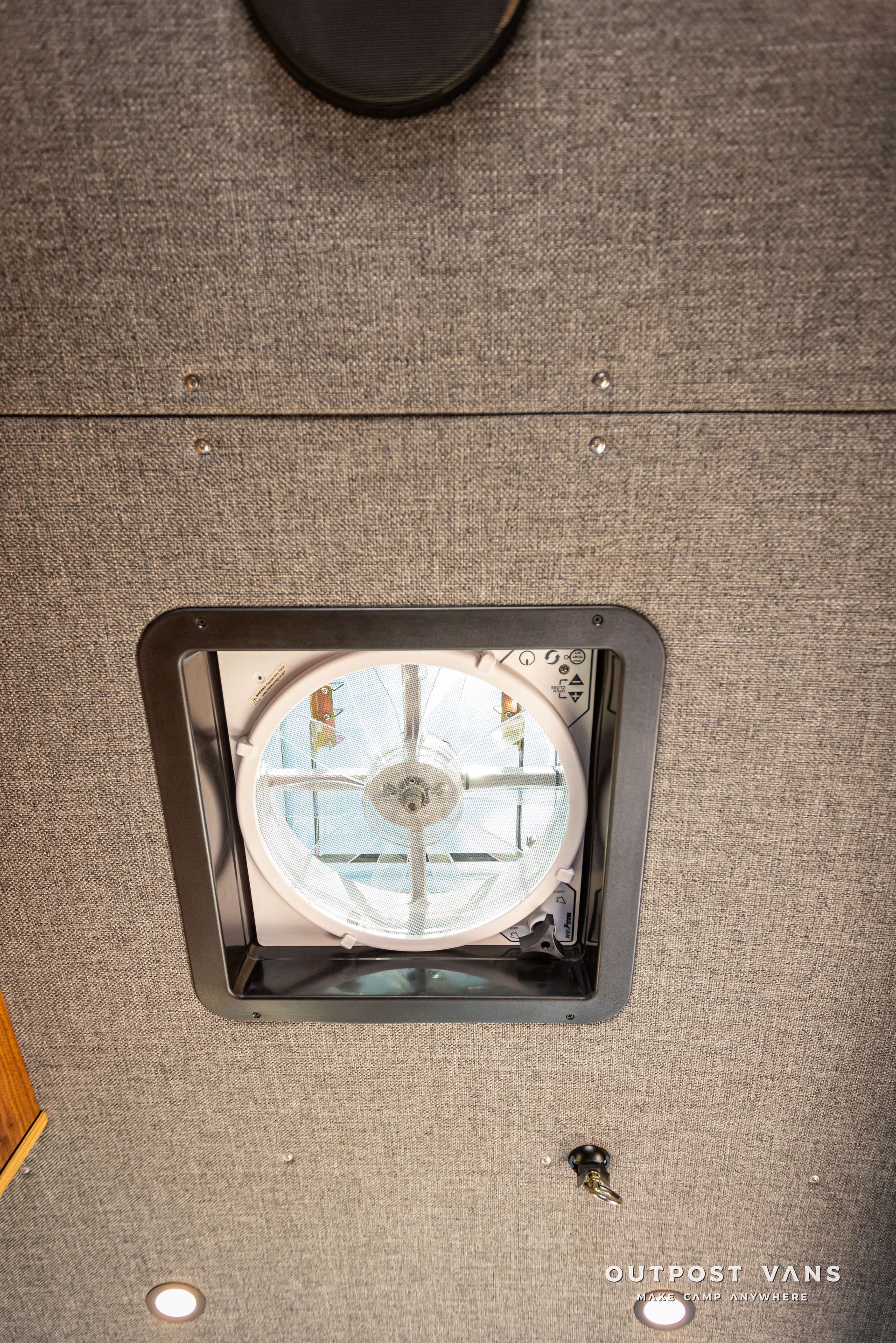 Outpost Vans custom built camper van Ford Transit 148 AWD. There is a fan in the ceiling of a building.
