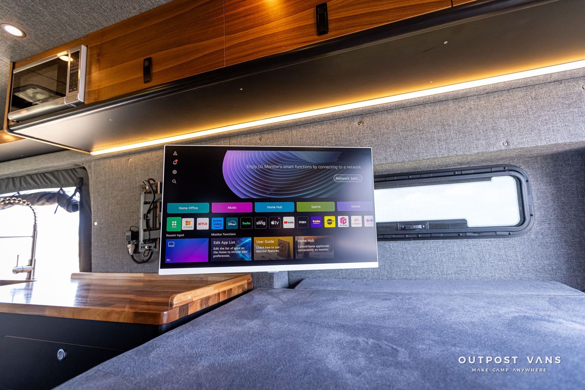 Outpost Vans custom built camper van Ford Transit 148 AWD. A computer monitor is hanging from the ceiling in a van.