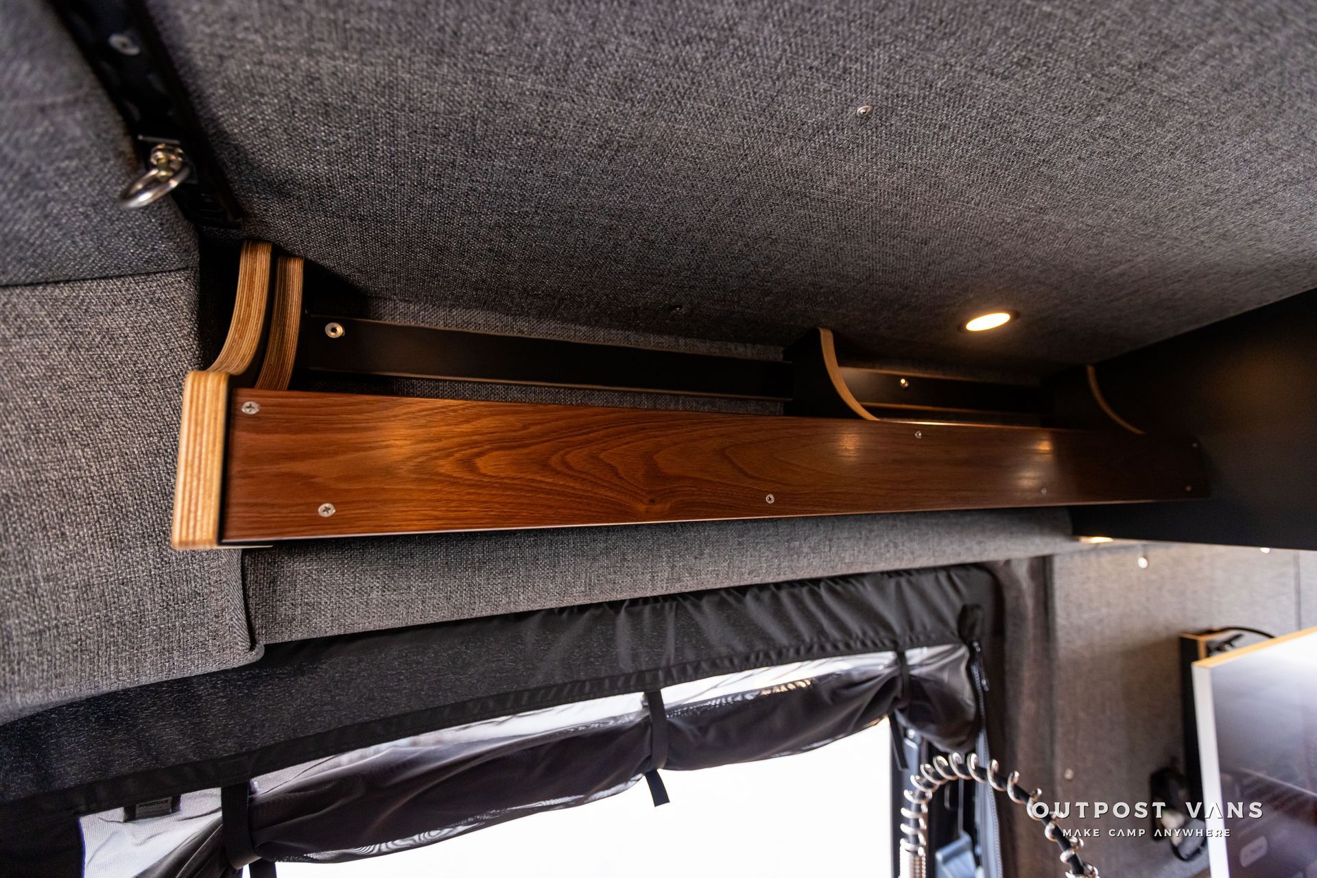 Outpost Vans custom built camper van Ford Transit 148 AWD. A wooden shelf is hanging from the ceiling of a van.