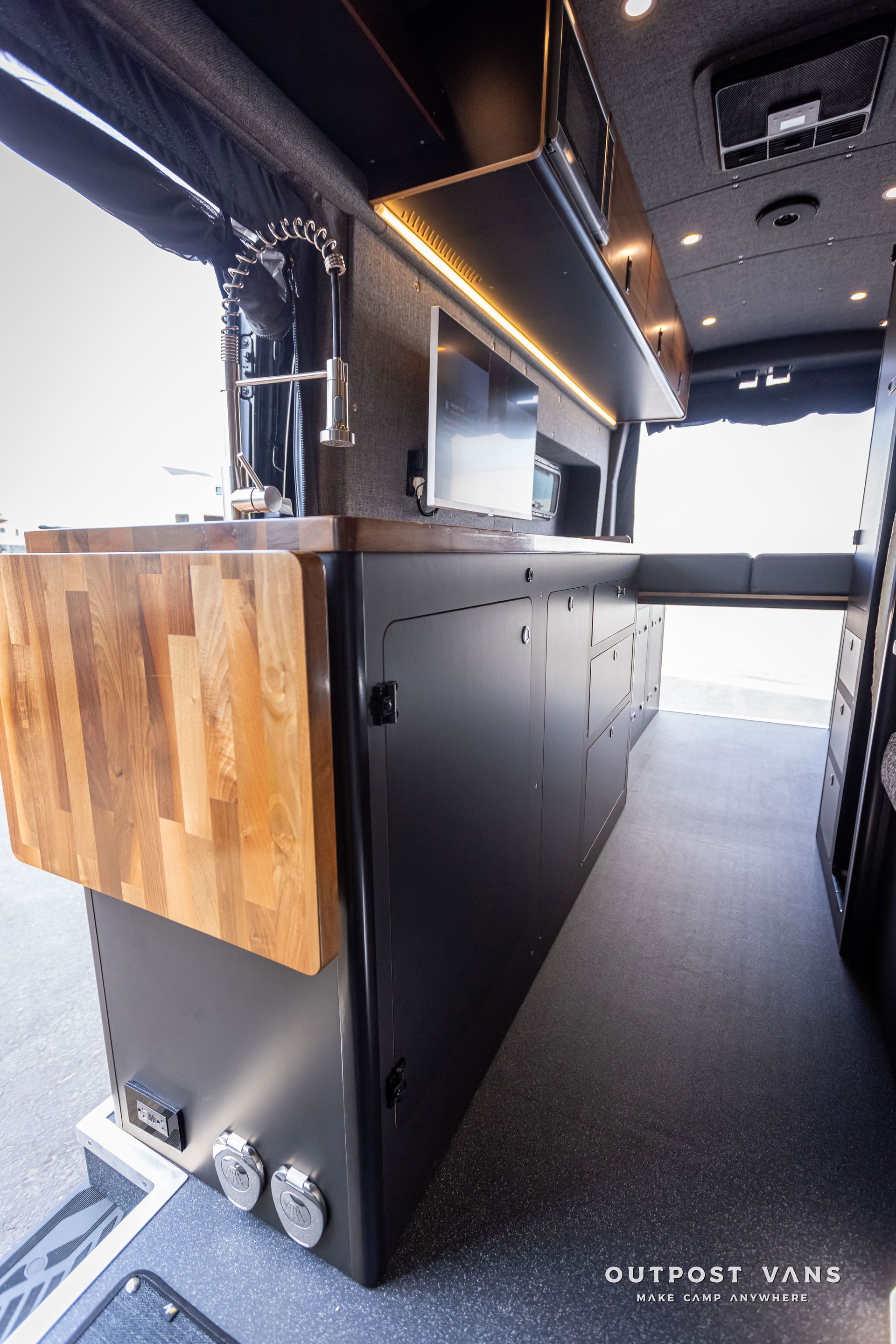 Outpost Vans custom built camper van Ford Transit 148 AWD. A kitchen in a van with a wooden counter top.