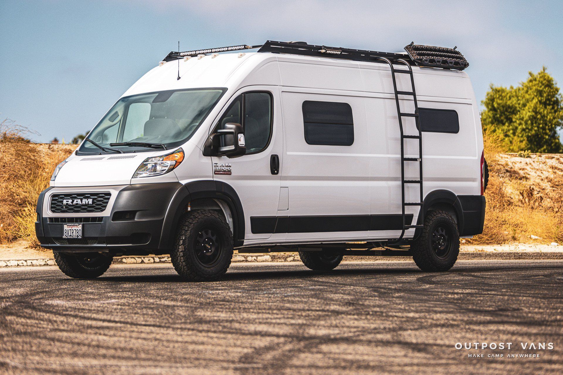 a white van with a ladder on the roof is parked on the side of the road .