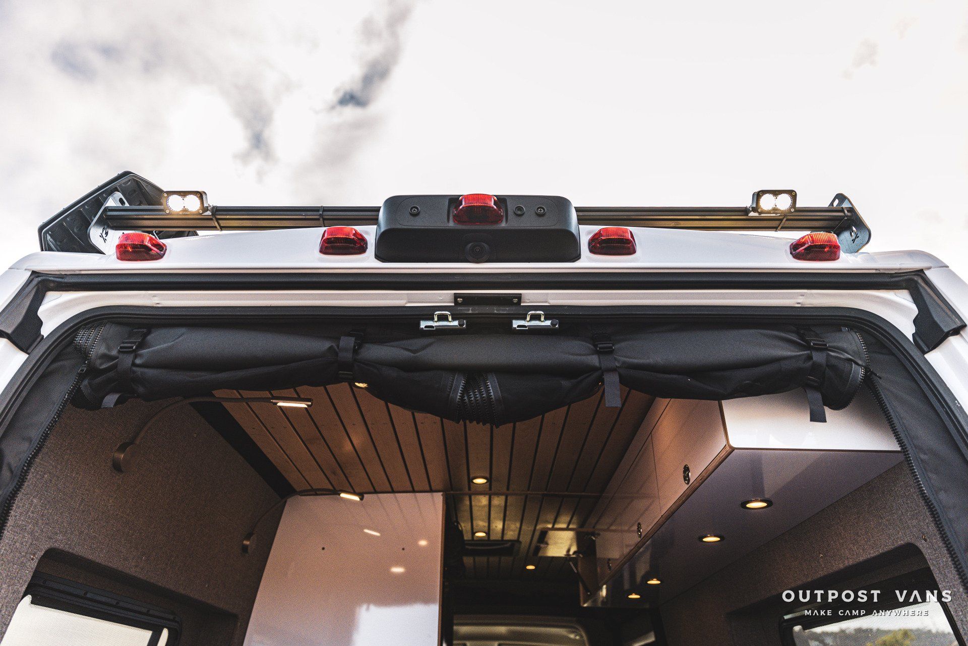 The back of a van with the door open and a roof rack.
