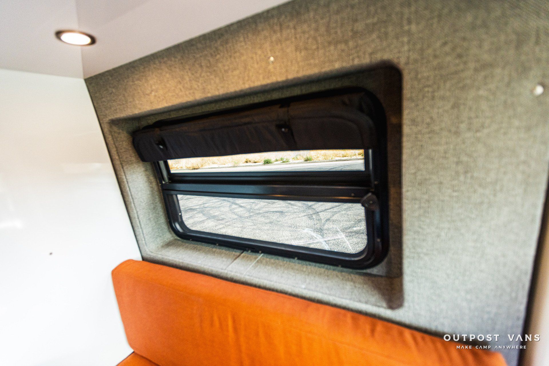 a window in the ceiling of a van with an orange couch .