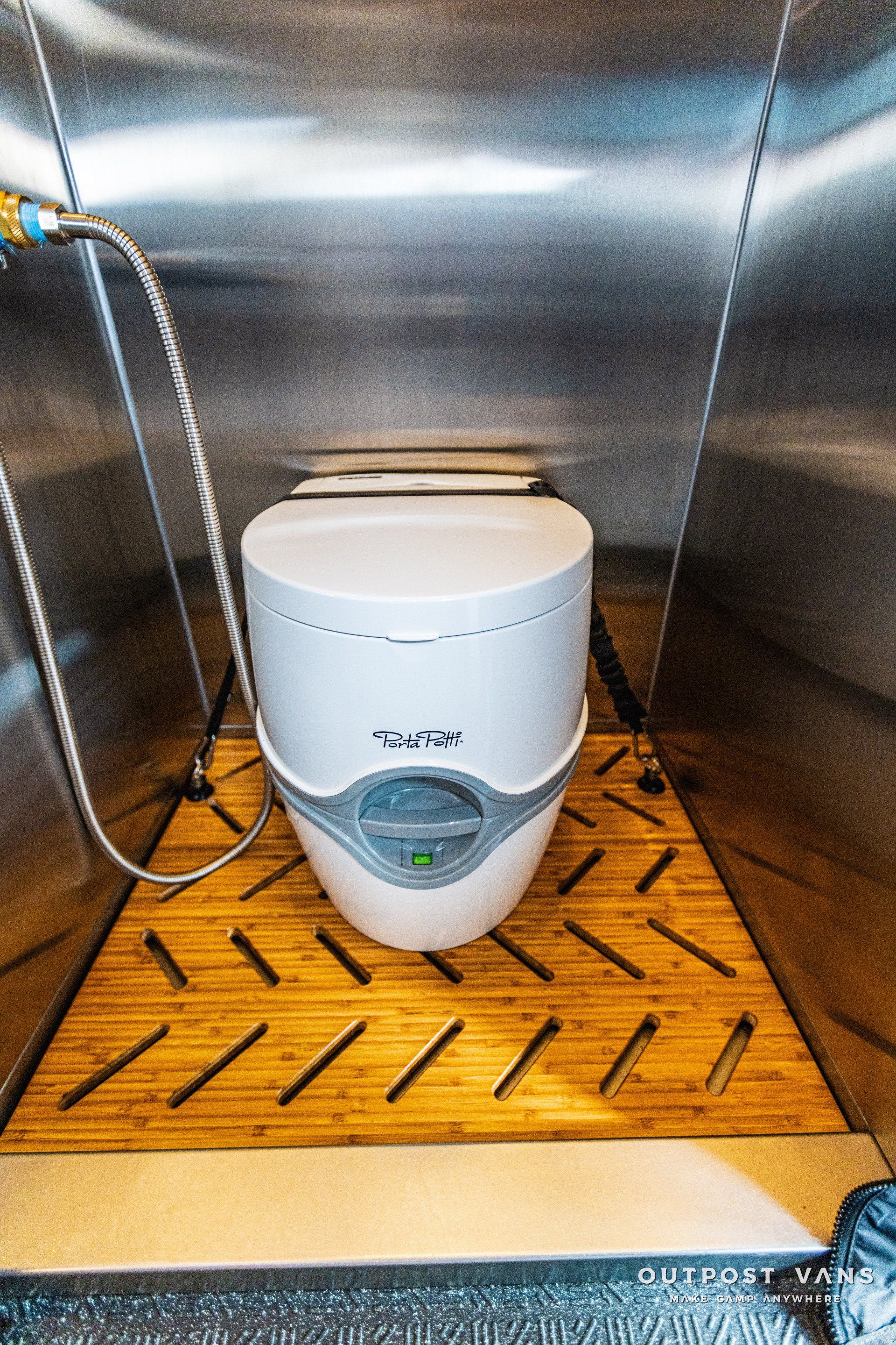 A white toilet is sitting on a wooden floor in a bathroom.