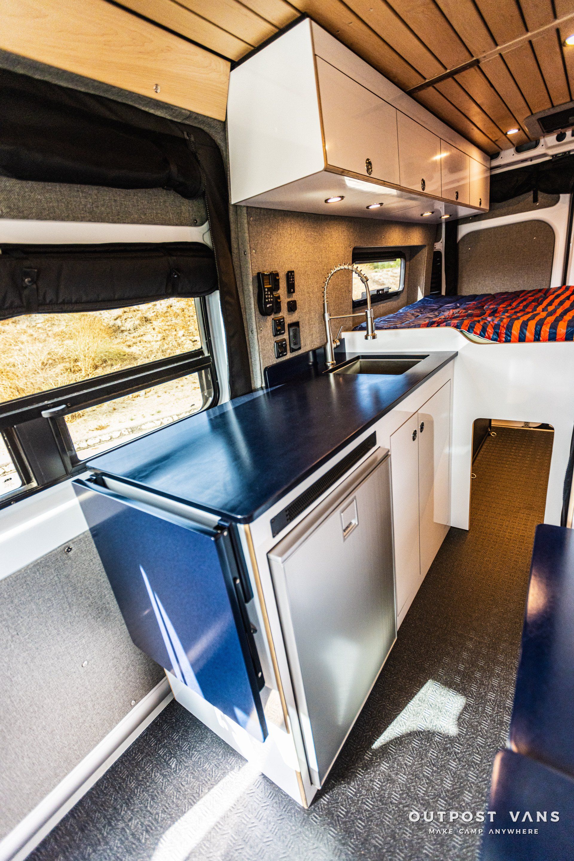The inside of a camper van with a kitchen and a bed.
