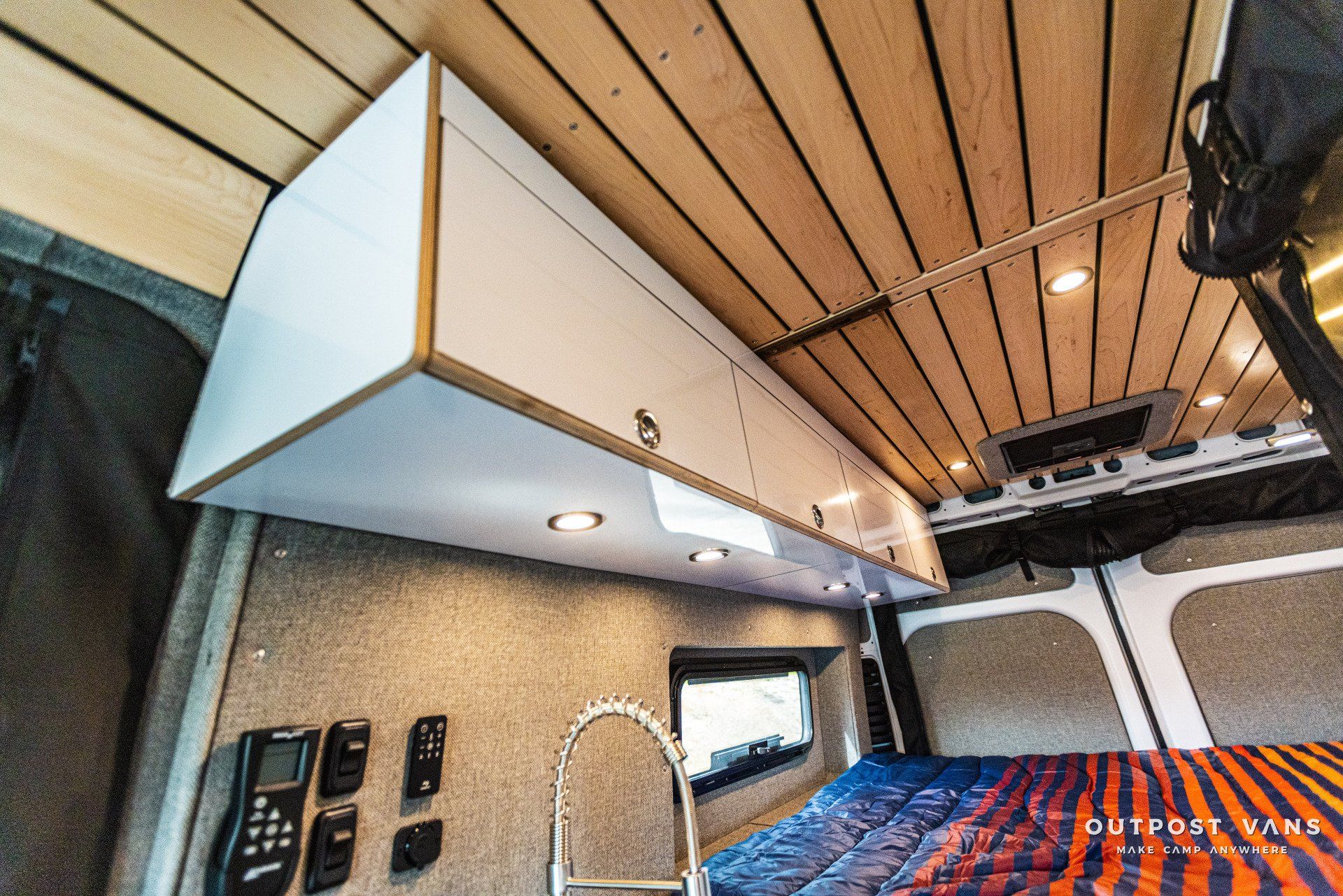 A van with a wooden ceiling and a bed in the back.