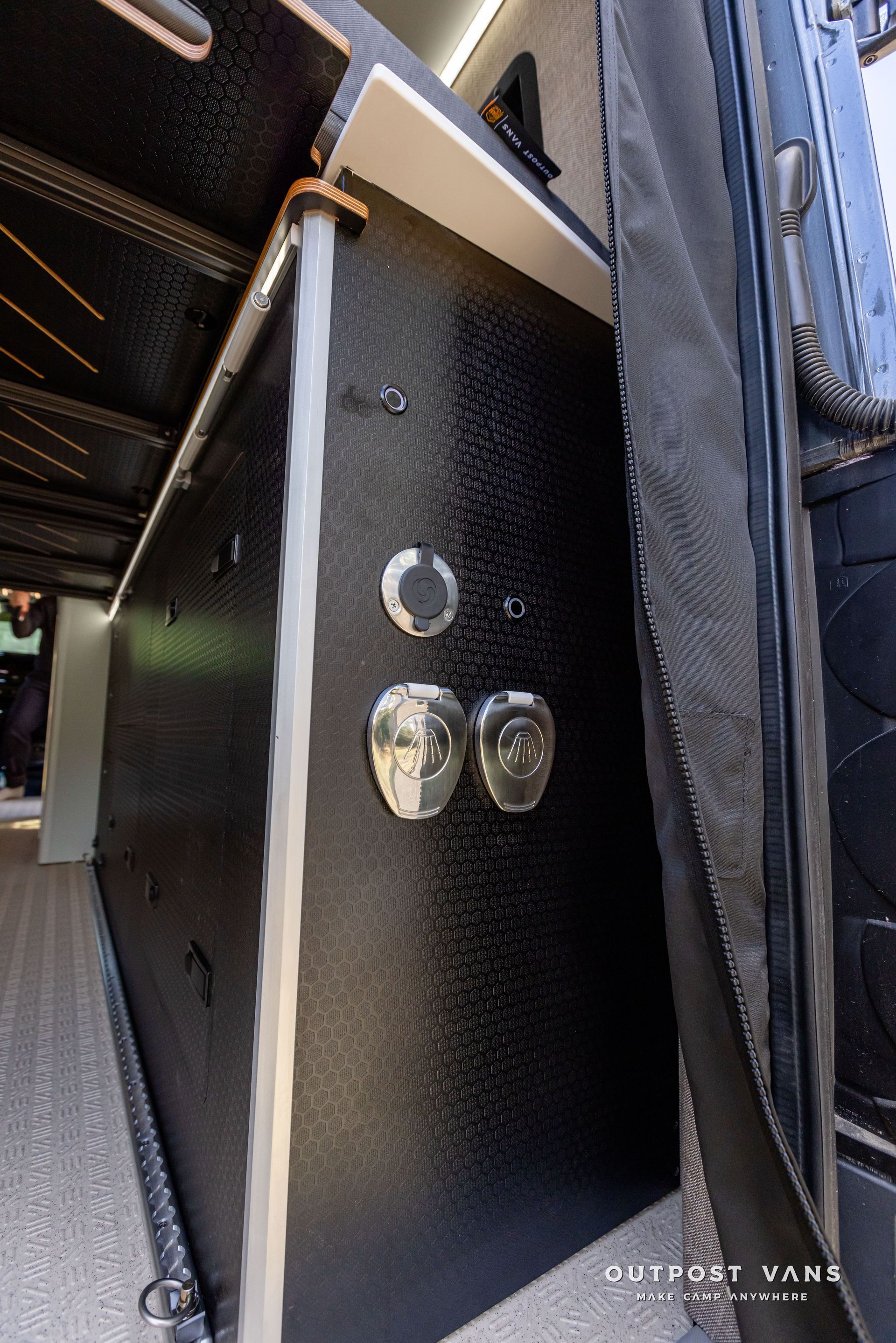 A close up of a black wall with a few buttons on it. Outpost vans Sprinter 170 AWD.