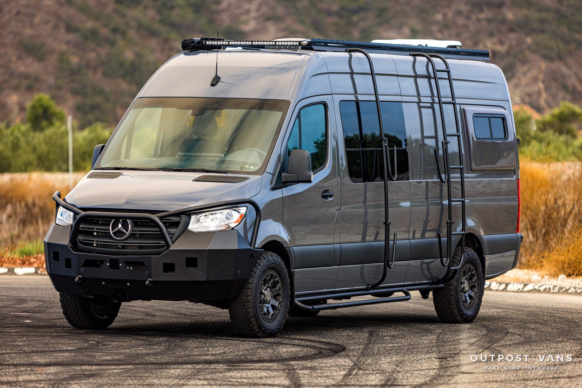 A mercedes sprinter van with a ladder on the side is parked on the side of the road.
