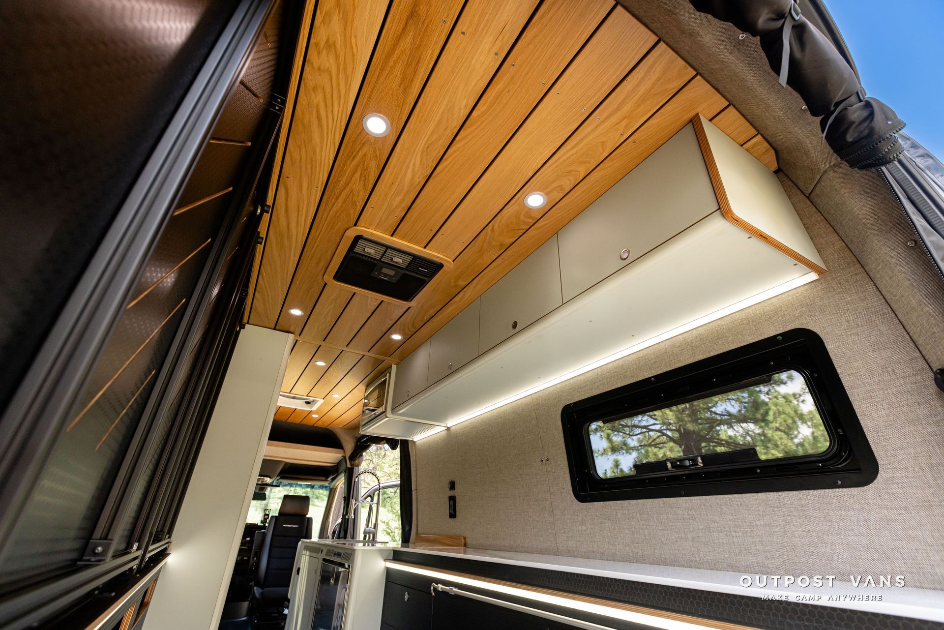 The inside of a van with a wooden ceiling and a window. Outpost vans Sprinter 170 AWD.