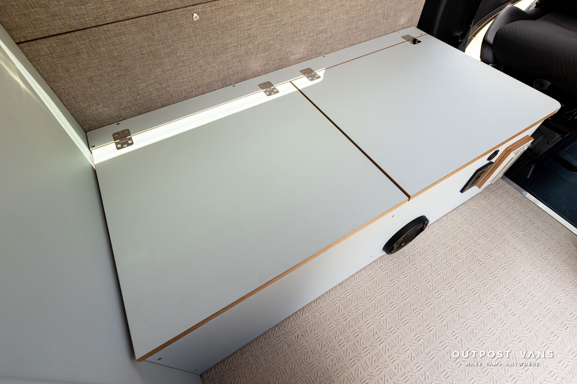 A white table with a drawer underneath it in a car. Outpost vans Sprinter 170 AWD.