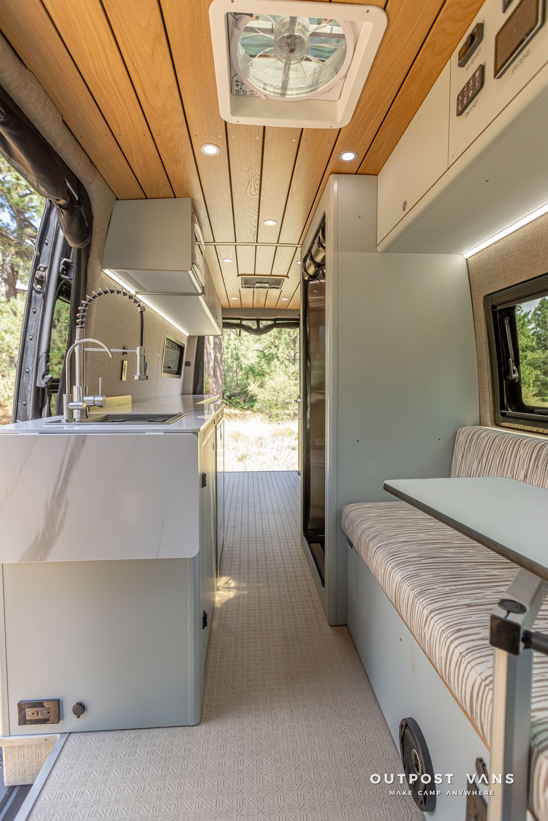 The inside of a camper van with a sink and a table. Outpost vans Sprinter 170 AWD.