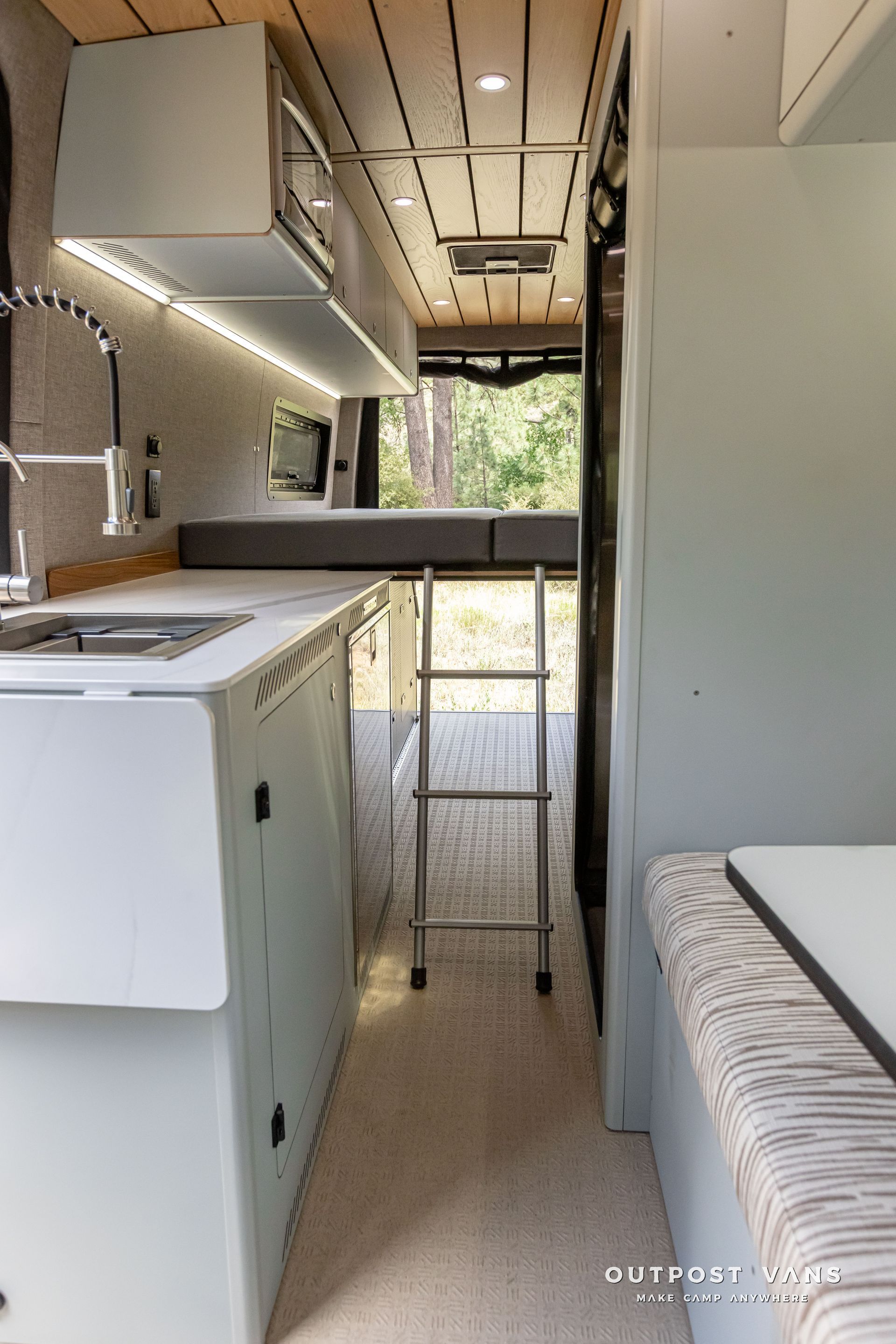 A kitchen in a van with a sink and a ladder. Outpost vans Sprinter 170 AWD.