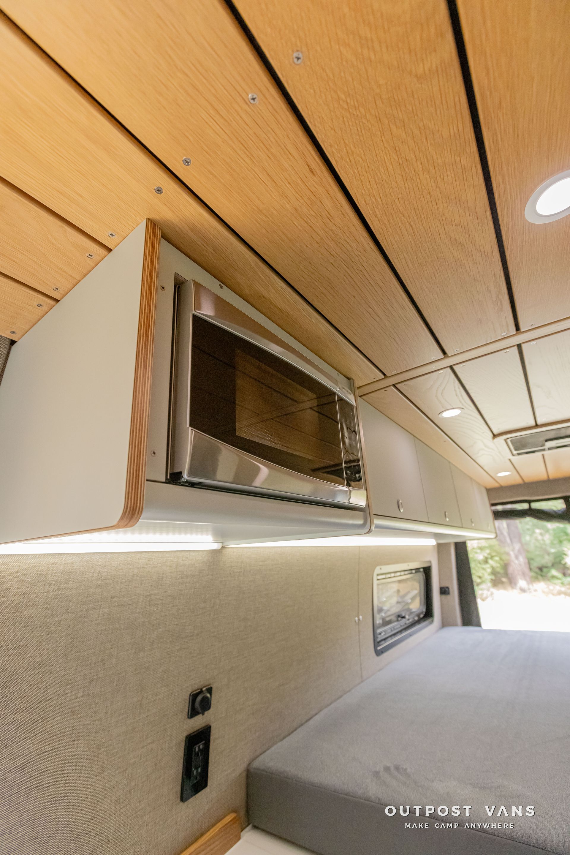 A microwave oven is built into the ceiling of a van. Outpost vans Sprinter 170 AWD.