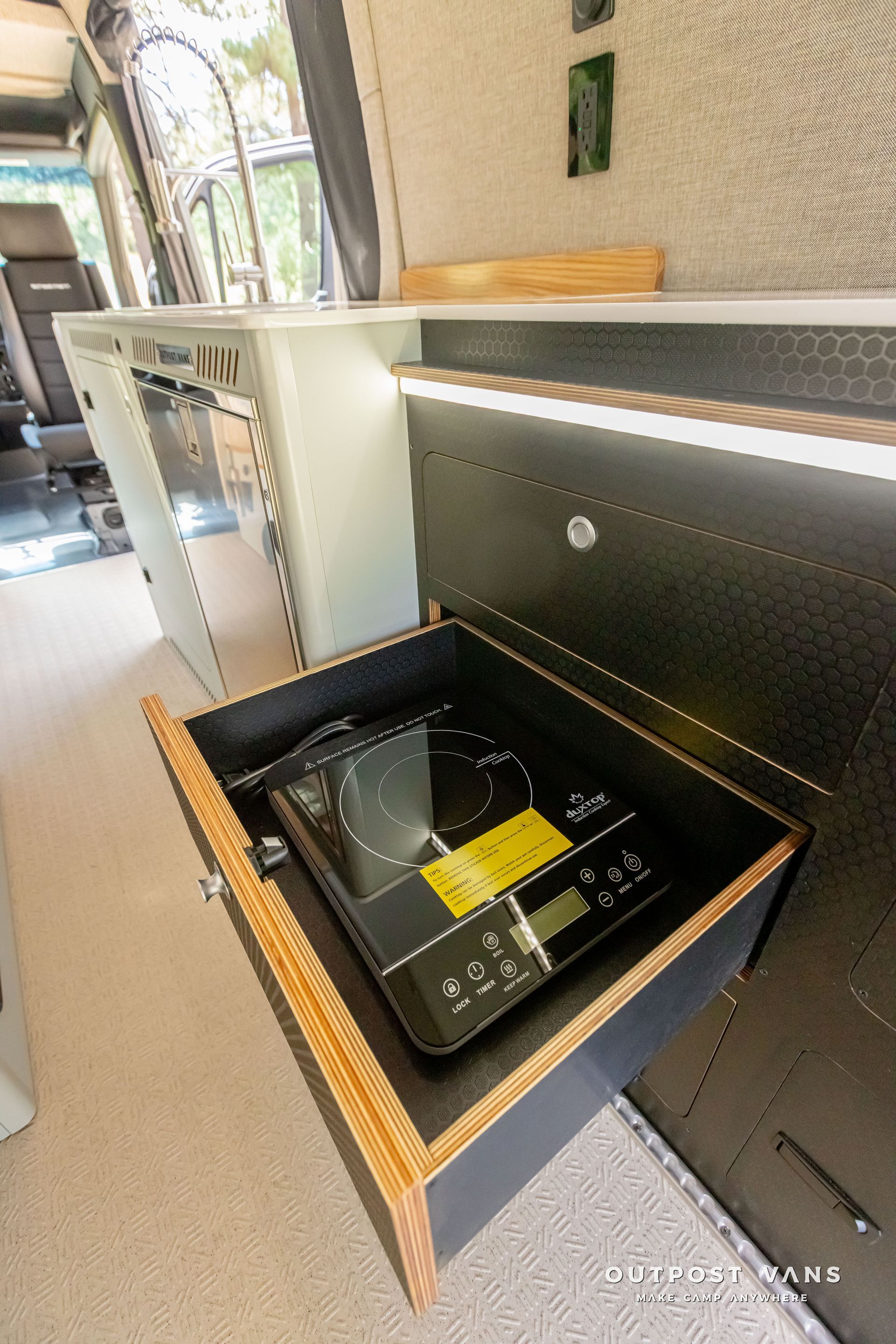 induction cooktop is sitting in a drawer in a camper van. Outpost vans Sprinter 170 AWD.