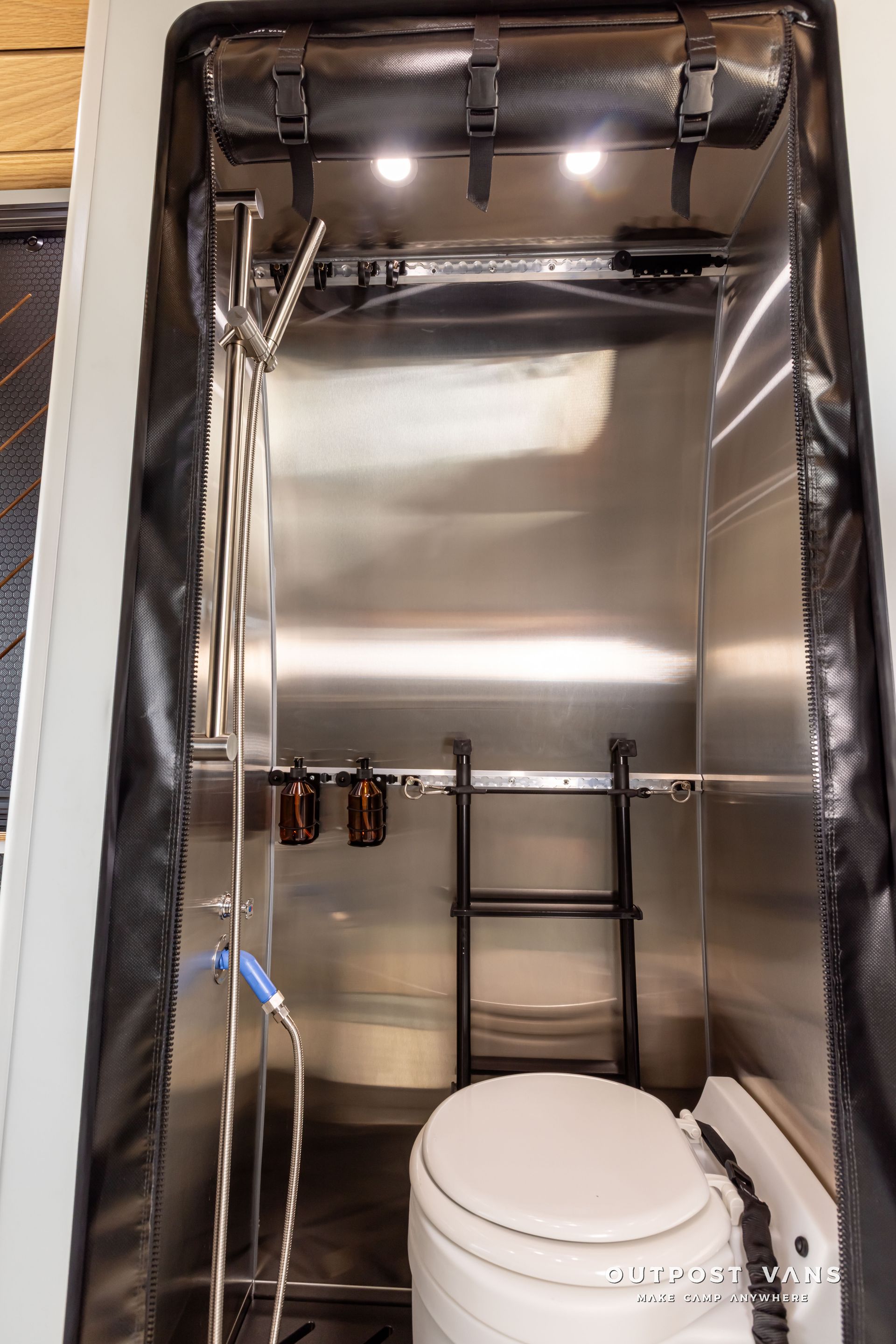 A bathroom with a toilet , shower and ladder. Outpost vans Sprinter 170 AWD.