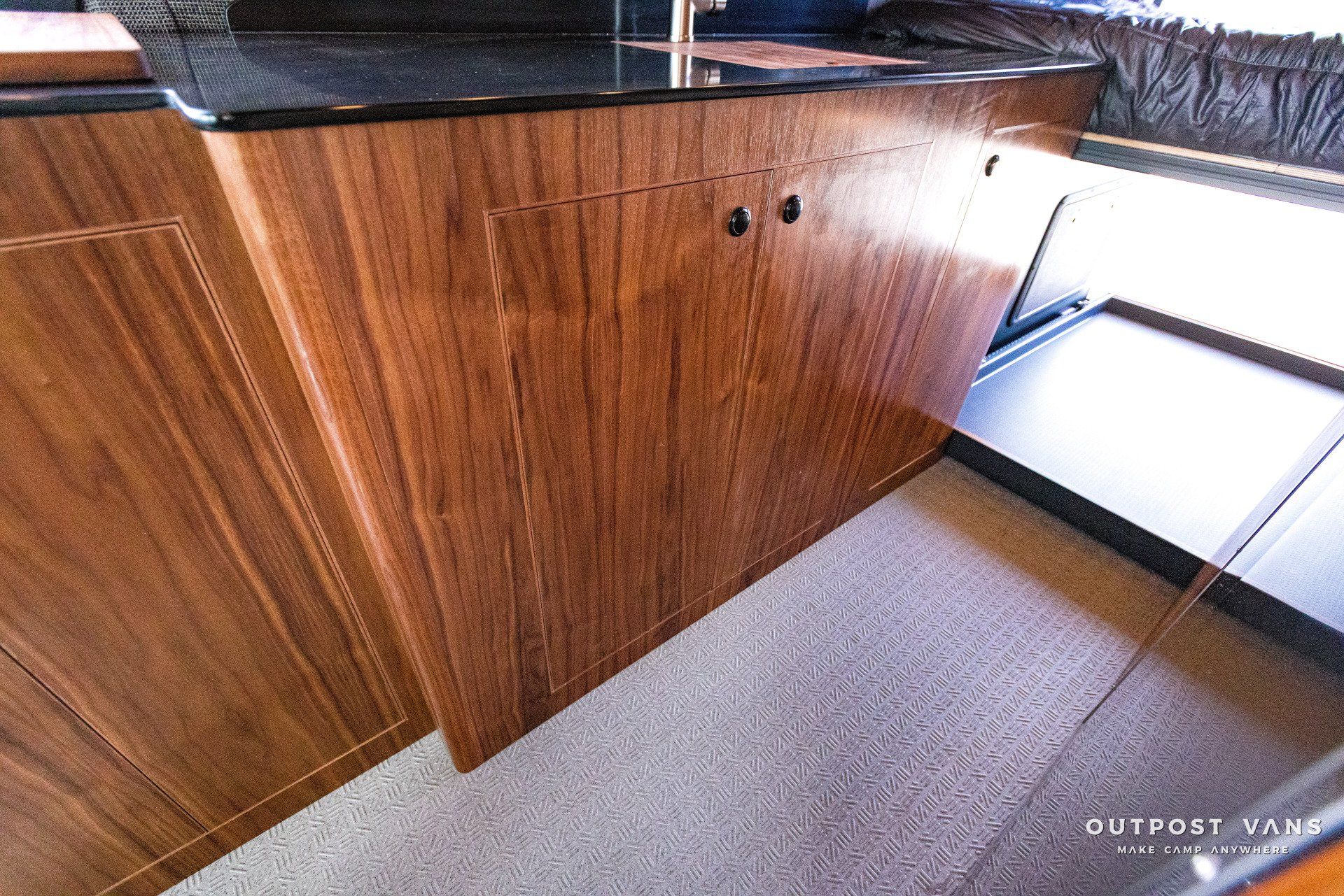 A kitchen with wooden cabinets and a black counter top.