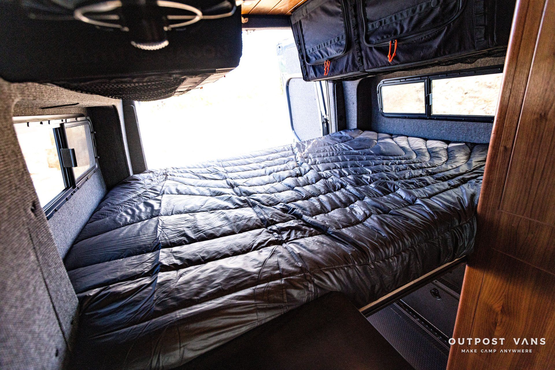 A bed in a van with the words outpost vans on the bottom