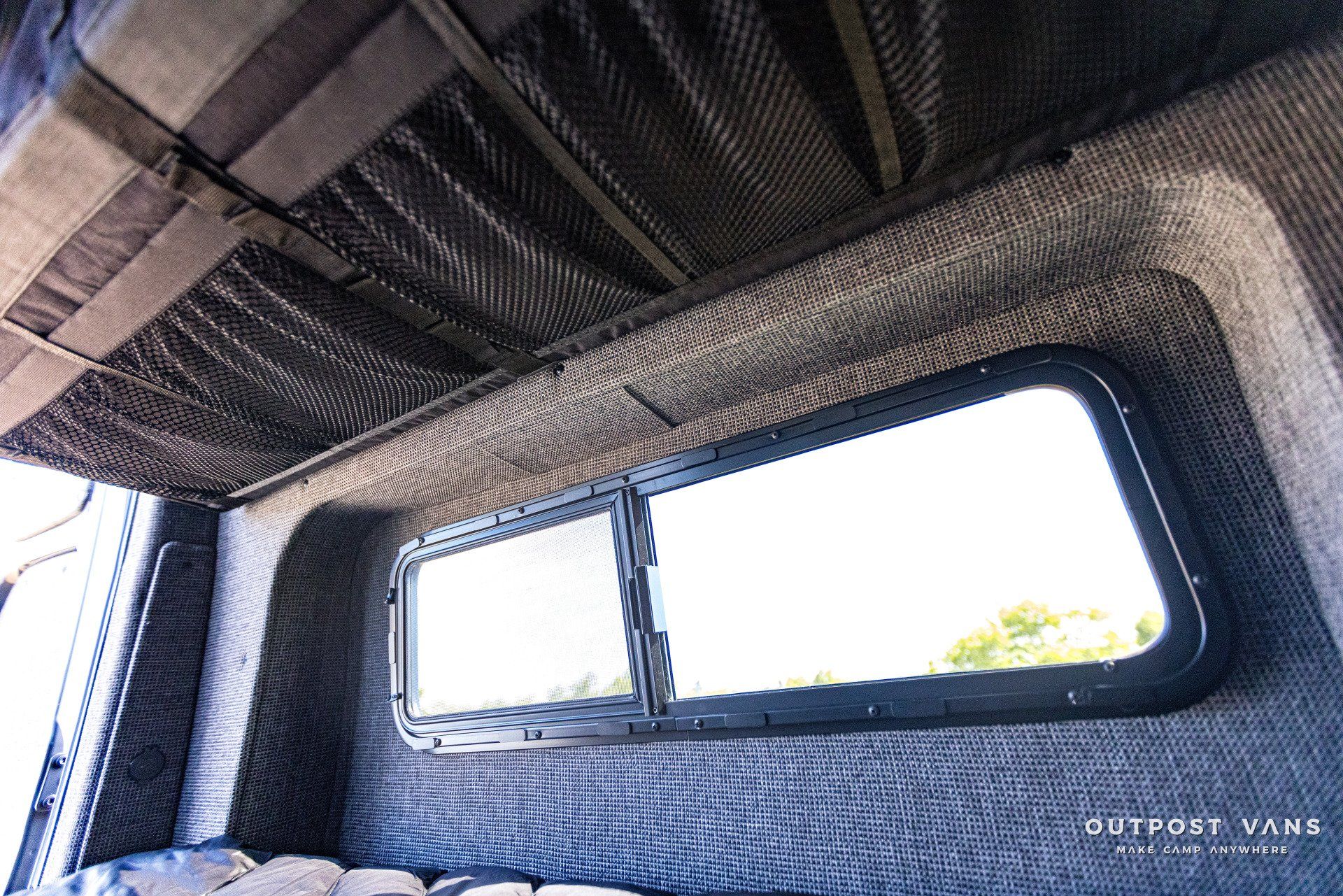 The inside of a van with a bed and a window.